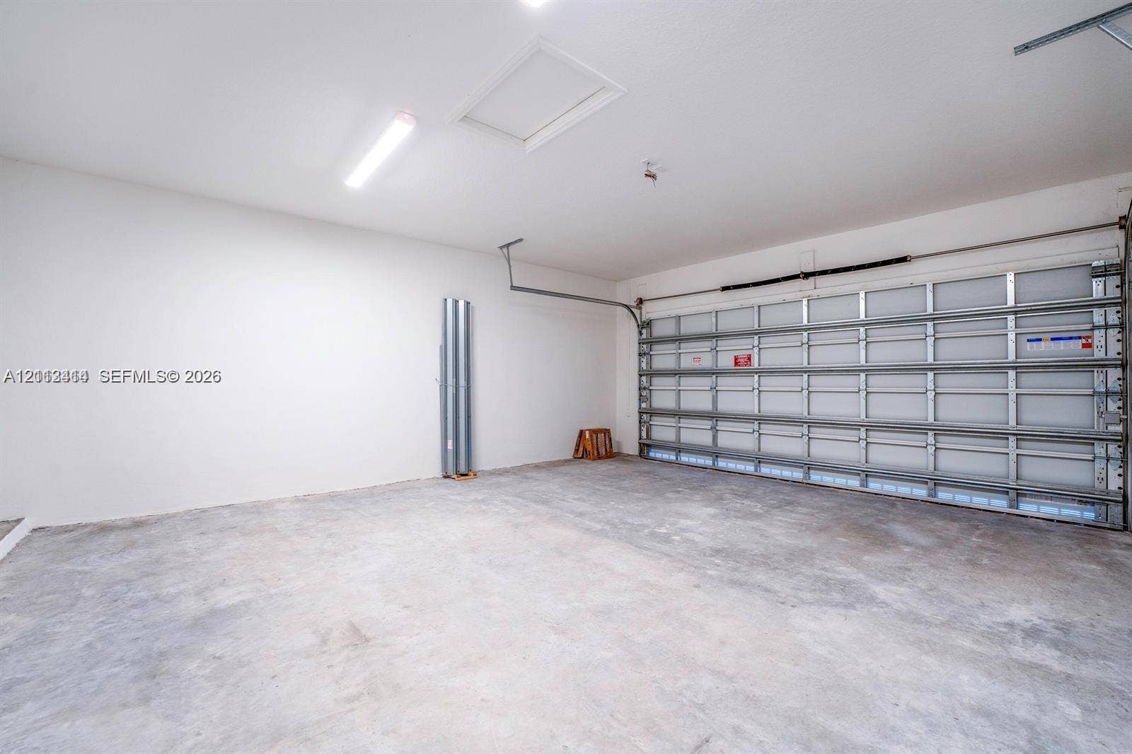 3024 Green Palm Court, #5838, Dania, Dania Beach, FL 33312 Finished garage featuring smooth-finish walls, exposed panel-style garage door, concrete flooring, and overhead lighting