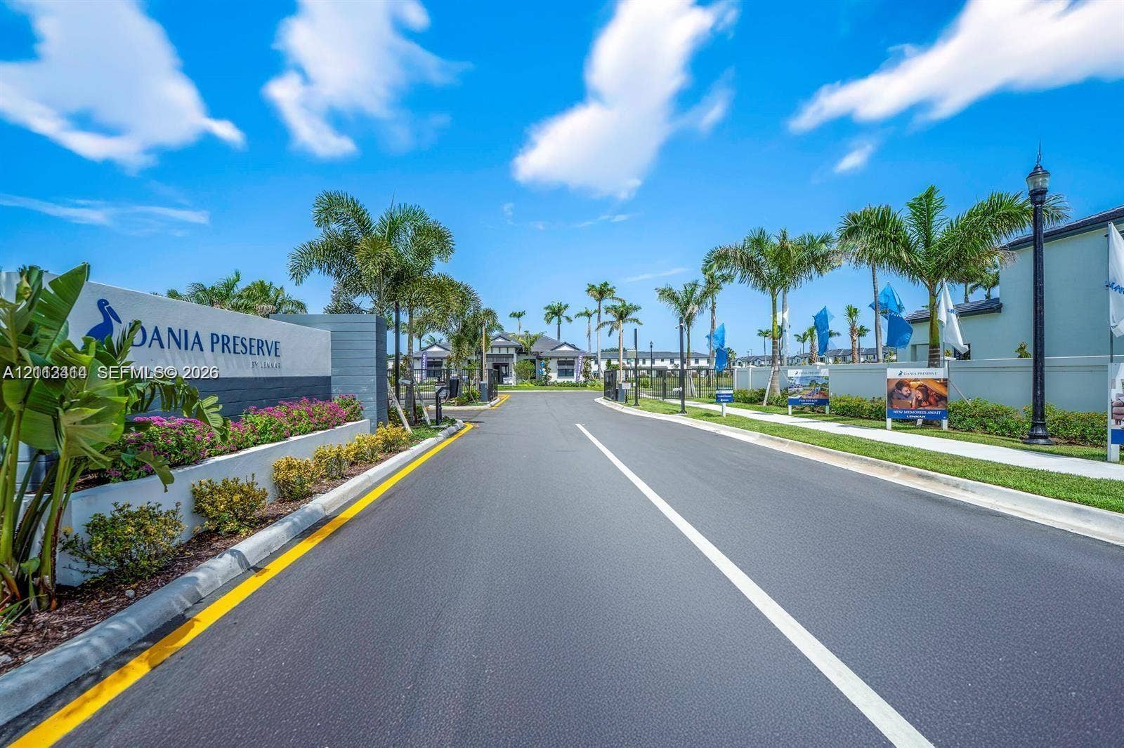 3024 Green Palm Court, #5838, Dania, Dania Beach, FL 33312 Gated community entrance featuring landscaped beds, mature palm trees, paved roadway, and decorative monument signage