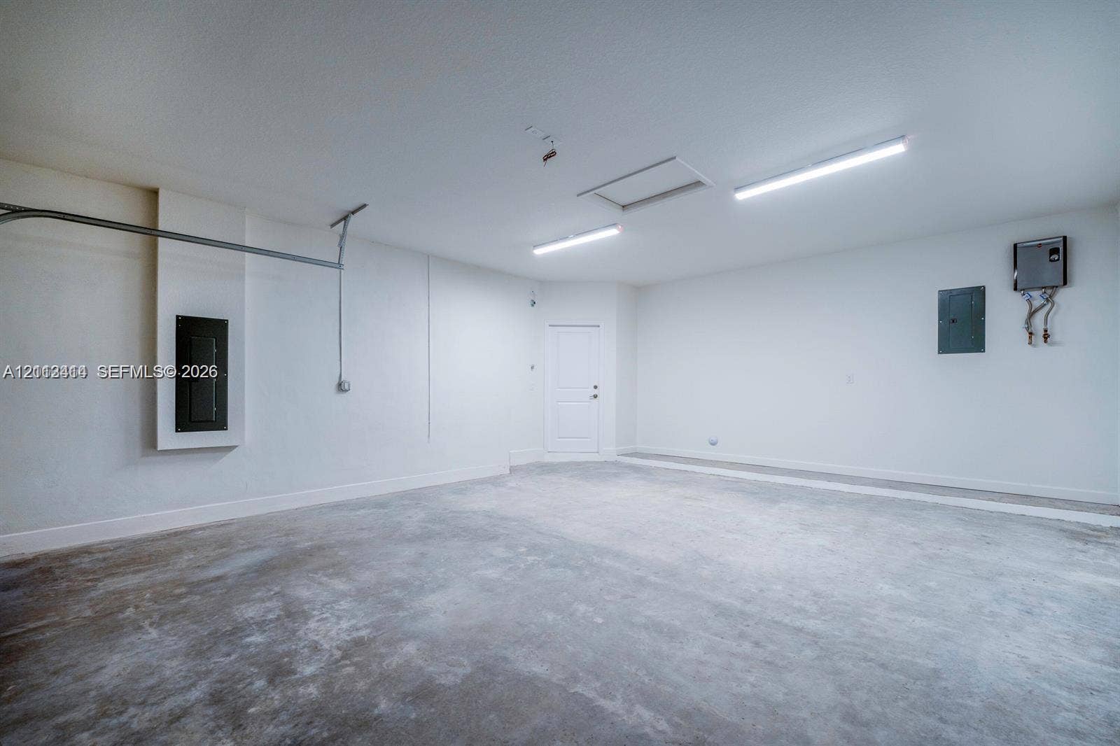 3024 Green Palm Court, #5838, Dania, Dania Beach, FL 33312 Finished garage featuring smooth walls, concrete flooring, dual overhead LED lighting fixtures, and an attic access panel