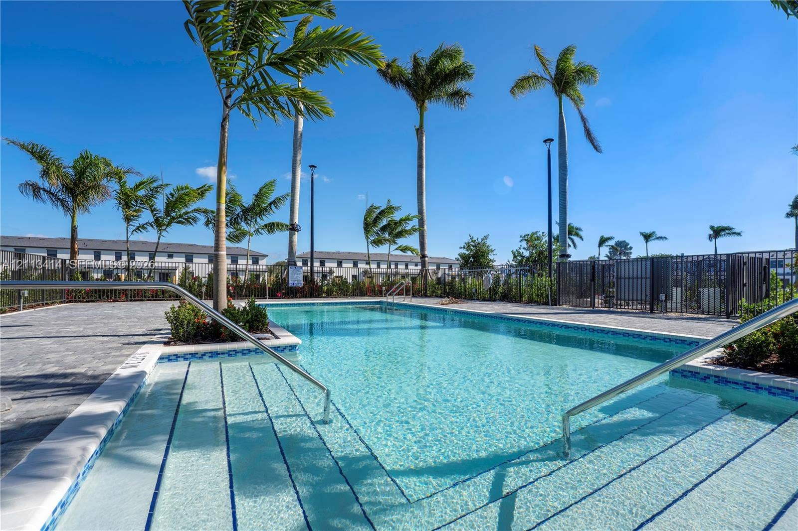 3024 Green Palm Court, #5838, Dania, Dania Beach, FL 33312 Swimming pool featuring stepped entry, stainless steel handrails, perimeter pavers, and mature palm trees