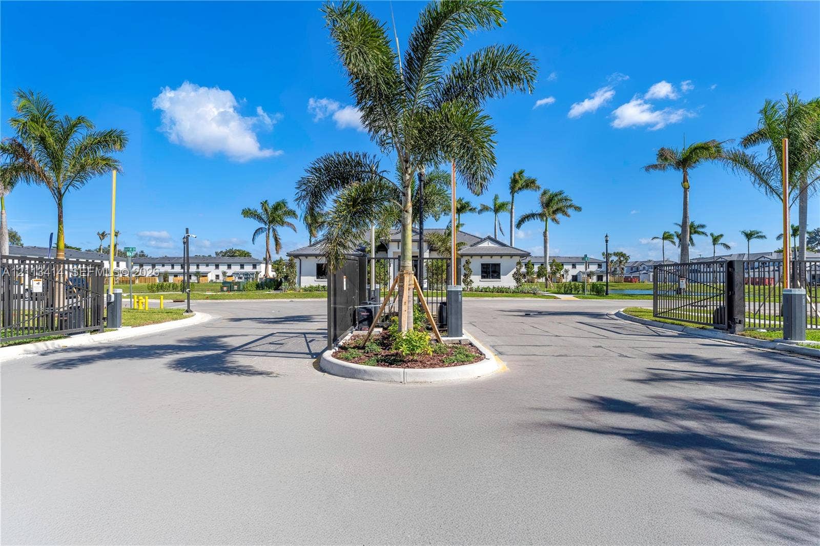 3024 Green Palm Court, #5838, Dania, Dania Beach, FL 33312 Gated community entrance featuring automated security gates, perimeter metal fencing, and palm-lined landscaping