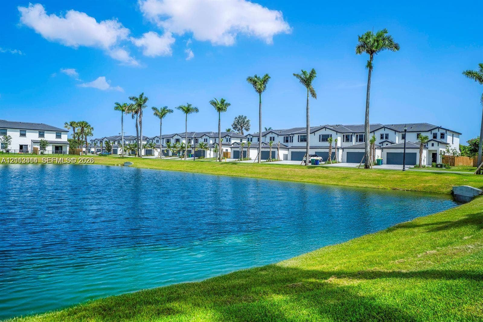 3024 Green Palm Court, #5838, Dania, Dania Beach, FL 33312 Waterfront exterior featuring a manicured lawn, established palm trees, and multi-unit residential structures with attached garages