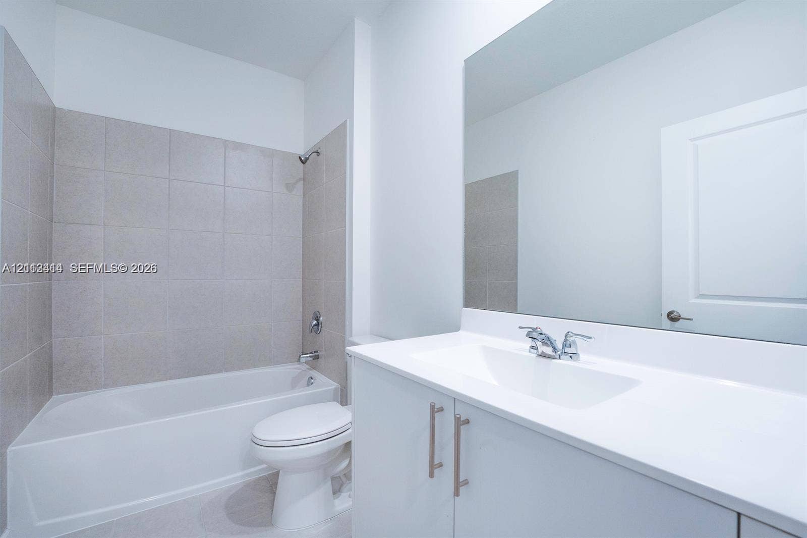 3024 Green Palm Court, #5838, Dania, Dania Beach, FL 33312 Bathroom featuring a white vanity cabinet with a solid surface countertop, an undermount sink with chrome fixtures, a full-width wall mirror, and a tile-surround bathtub