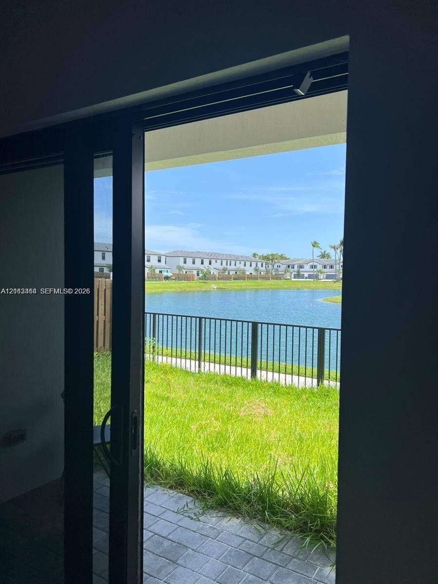 3024 Green Palm Court, #5838, Dania, Dania Beach, FL 33312 Black-framed sliding glass door opening to a paved patio, metal perimeter fencing, and waterfront scenery