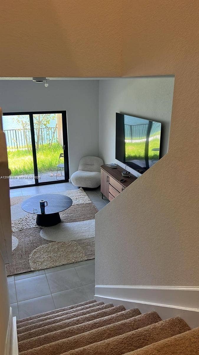 3024 Green Palm Court, #5838, Dania, Dania Beach, FL 33312 Interior space featuring neutral-toned carpeting on stairs, large-format tile flooring, and a sliding glass door providing external access