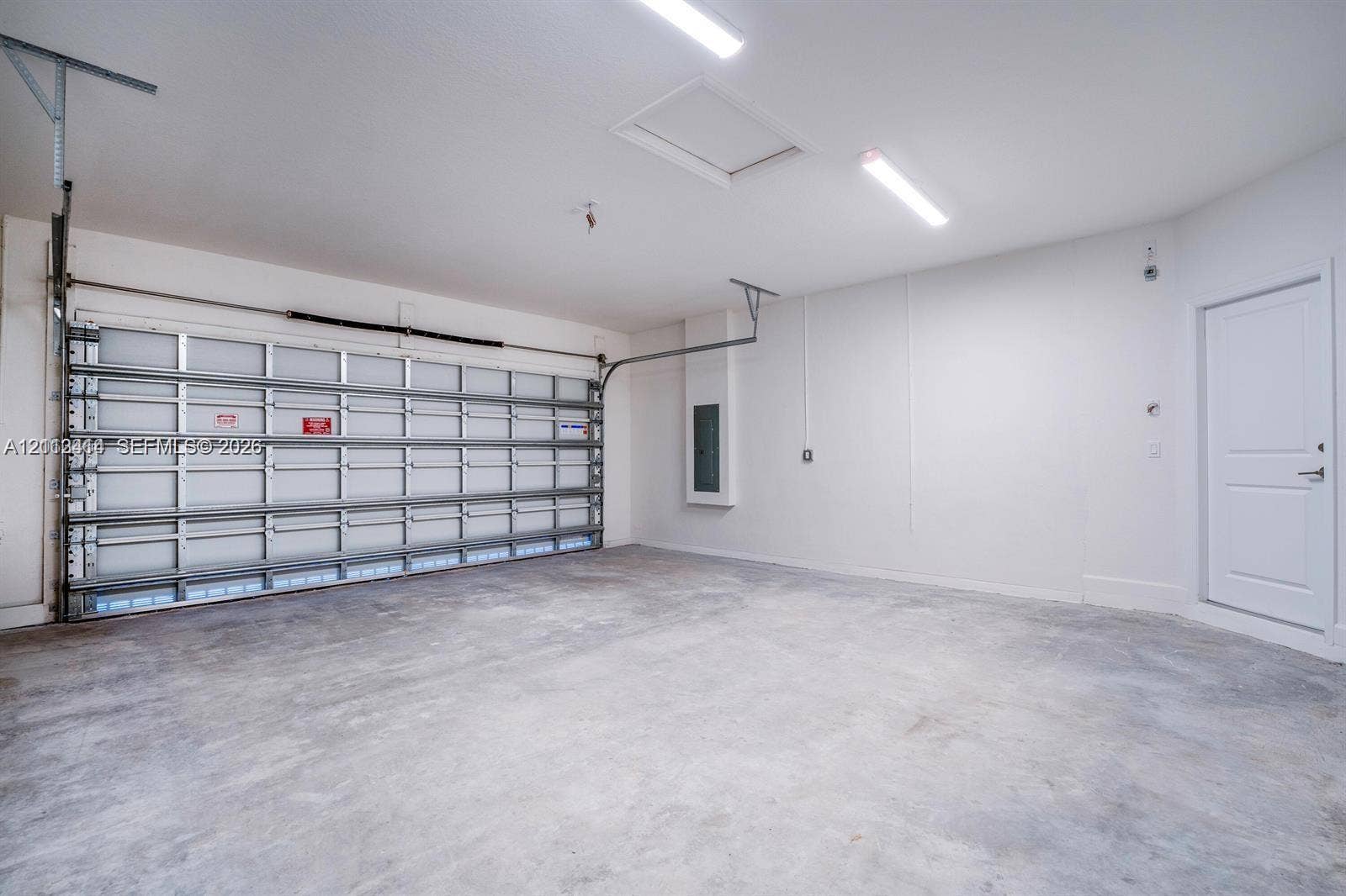 3024 Green Palm Court, #5838, Dania, Dania Beach, FL 33312 Garage interior featuring concrete flooring, LED strip lighting, an integrated electrical panel, and a paneled roll-up garage door