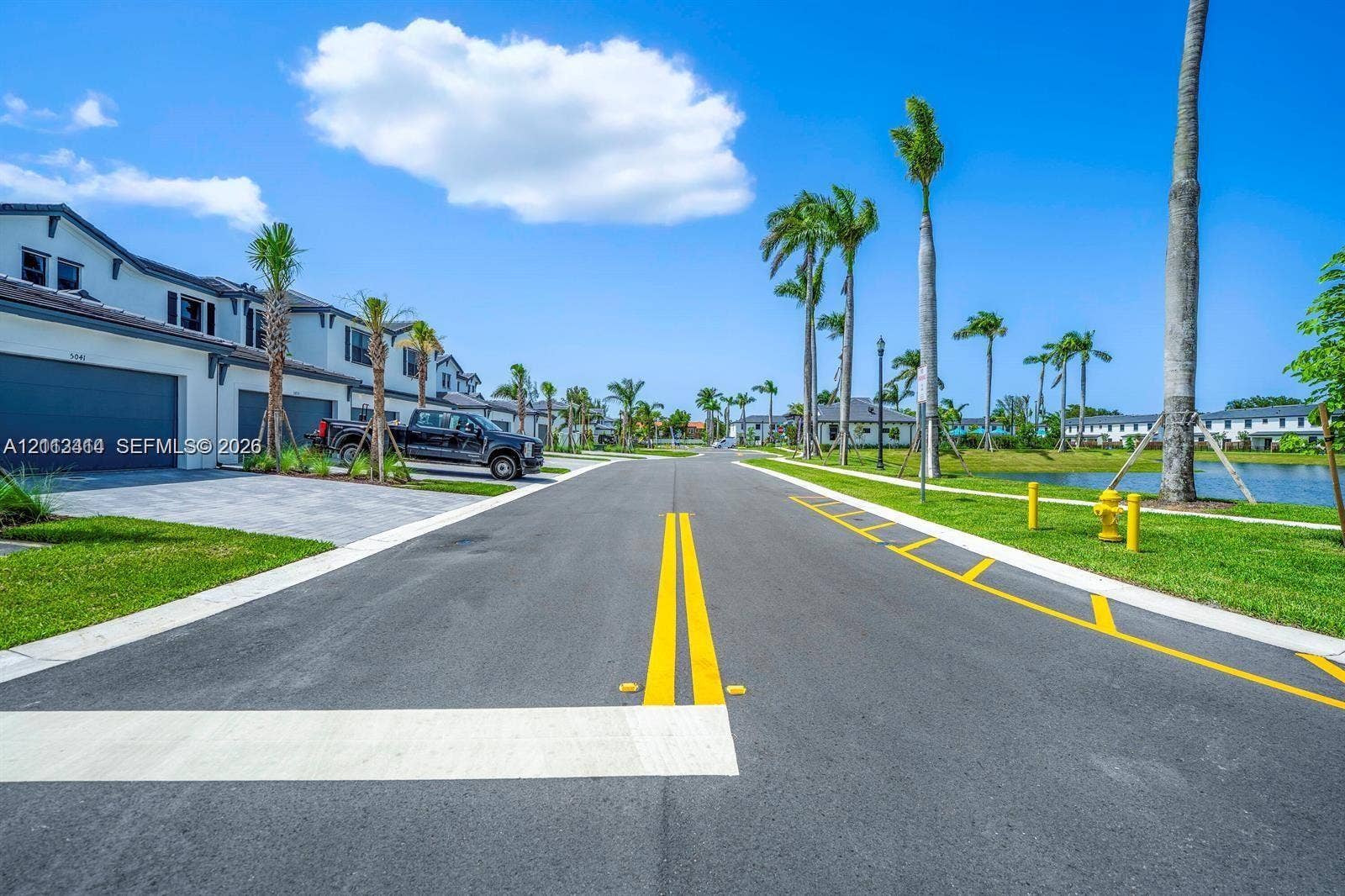 3024 Green Palm Court, #5838, Dania, Dania Beach, FL 33312 Paved street featuring curb-and-gutter infrastructure, manicured green space, and mature palm trees with a water feature