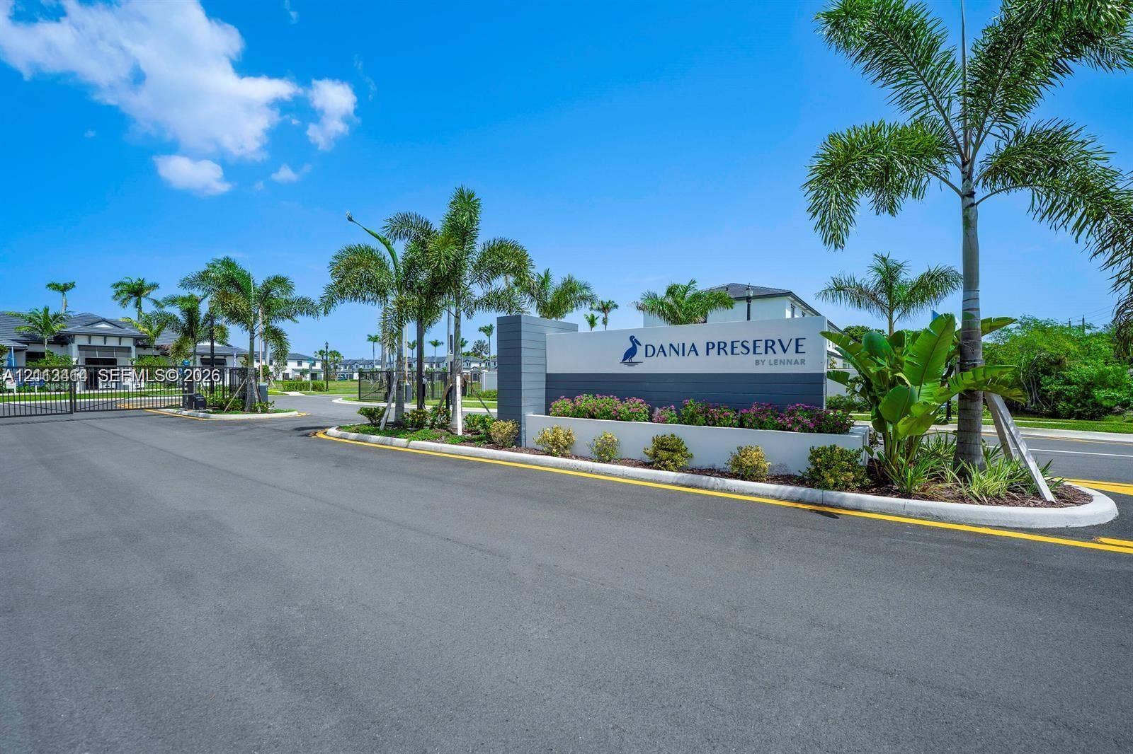 3024 Green Palm Court, #5838, Dania, Dania Beach, FL 33312 Gated community entrance featuring a masonry monument sign, asphalt paved roadway, and tropical landscaping
