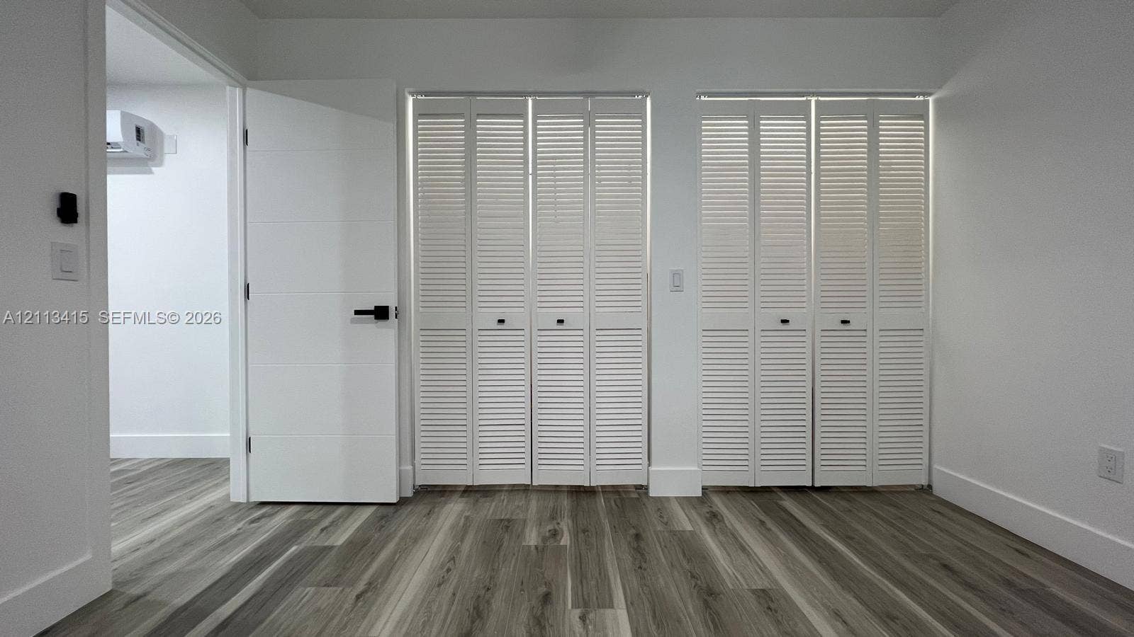 14442 SW 111th Street, #Studio, Miami, Miami, FL 33186 Wood-finish flooring, dual white louvered closet doors, and solid-core interior door with matte black hardware