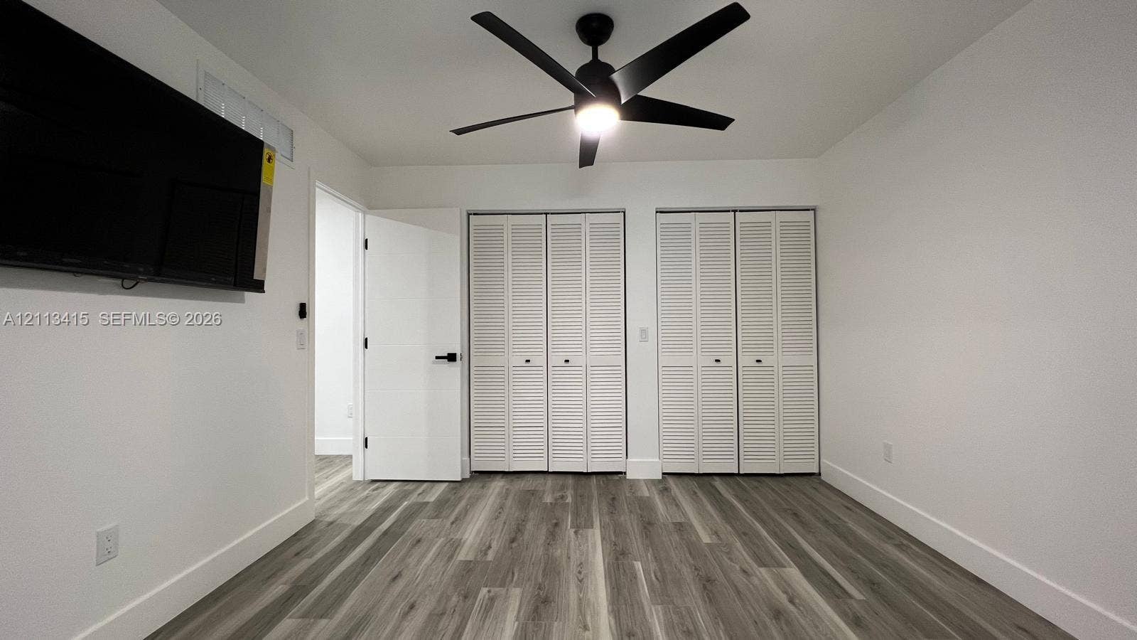 14442 SW 111th Street, #Studio, Miami, Miami, FL 33186 Wood-finish flooring, dual bi-fold louvered closets, matte black ceiling fan with integrated lighting, and matte black door hardware