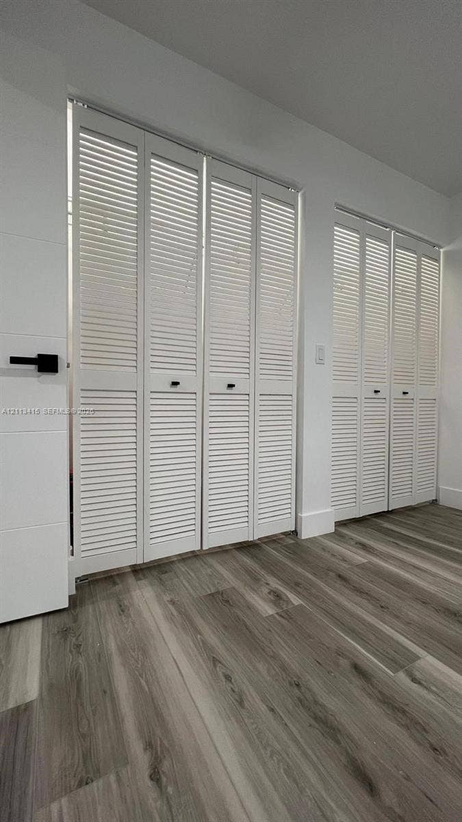 14442 SW 111th Street, #Studio, Miami, Miami, FL 33186 Wood-finish flooring paired with white louvered bifold doors featuring matte black hardware
