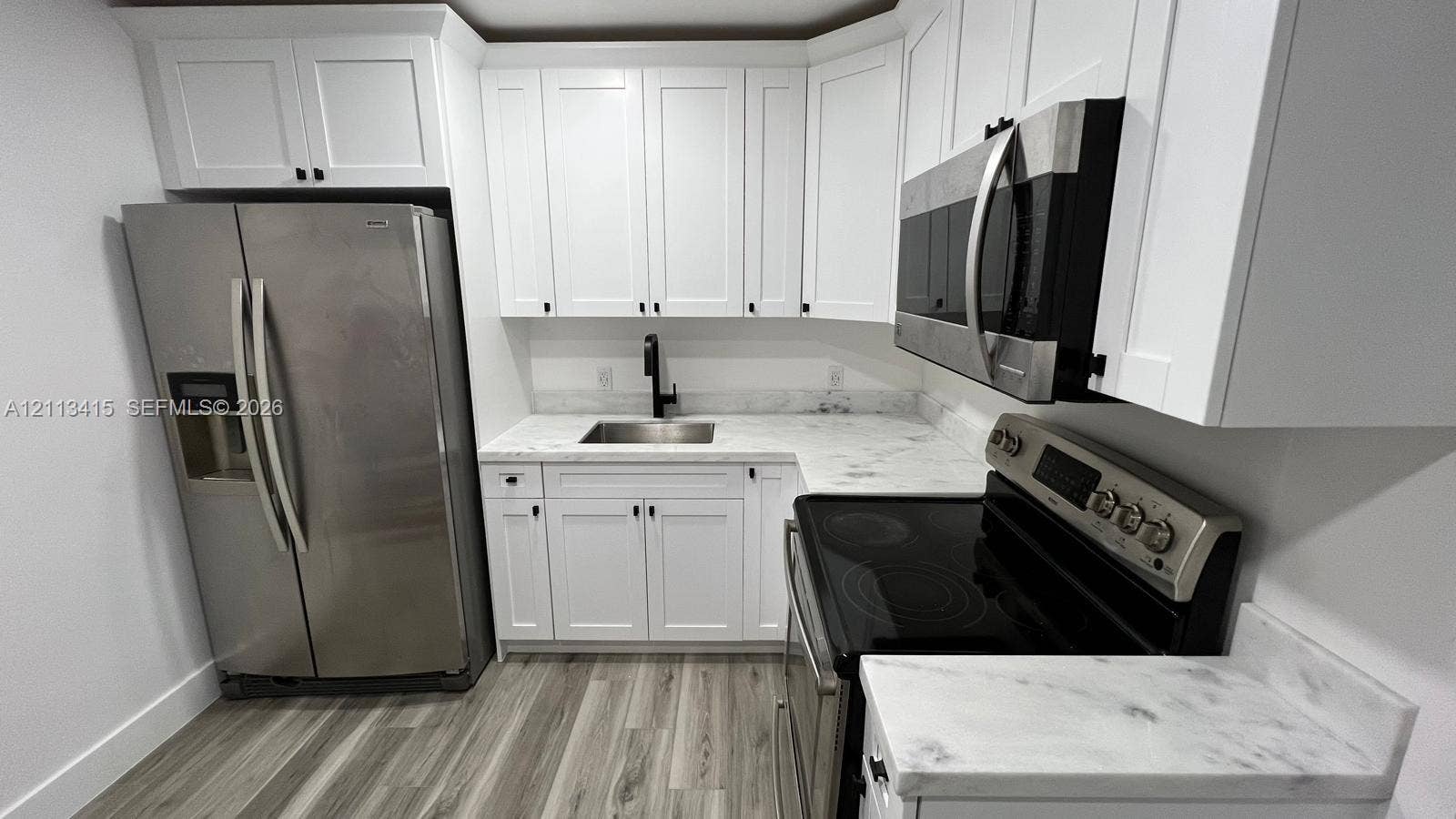 14442 SW 111th Street, #Studio, Miami, Miami, FL 33186 Kitchen featuring white Shaker-style cabinetry, stone-finish countertops, stainless steel appliances, a black pull-down faucet, and wood-finish flooring