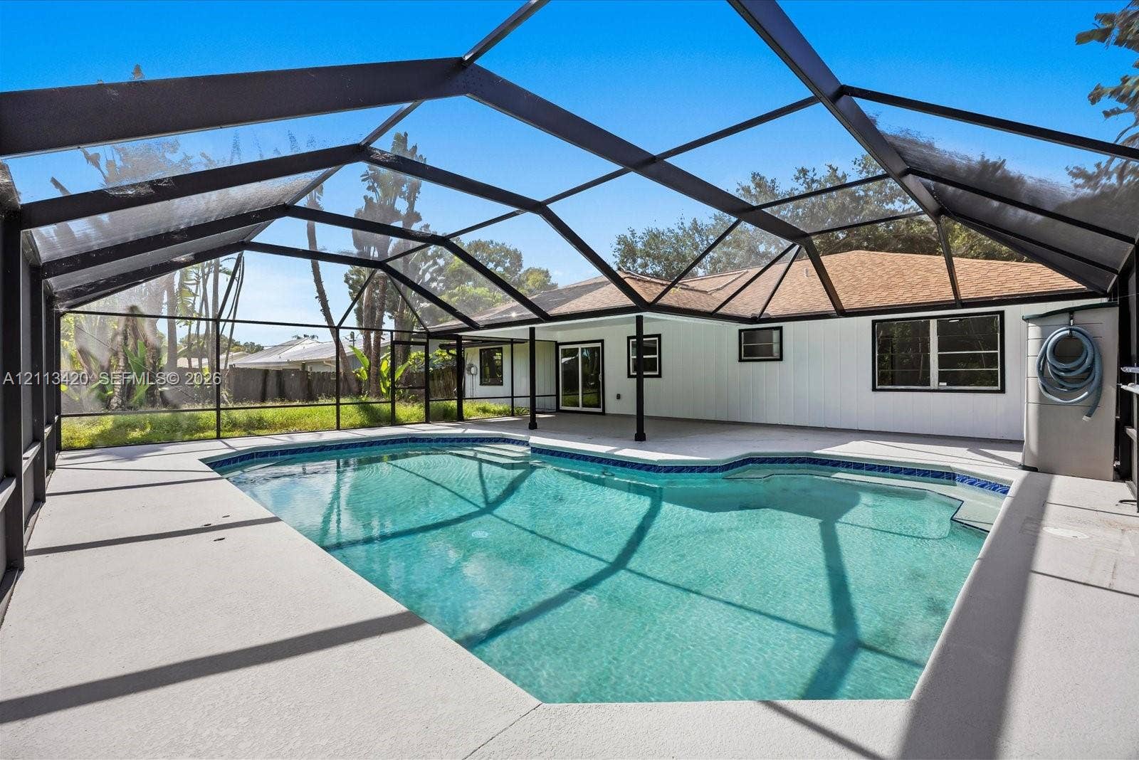 Screened-in patio featuring a swimming pool, concrete deck, and covered exterior area