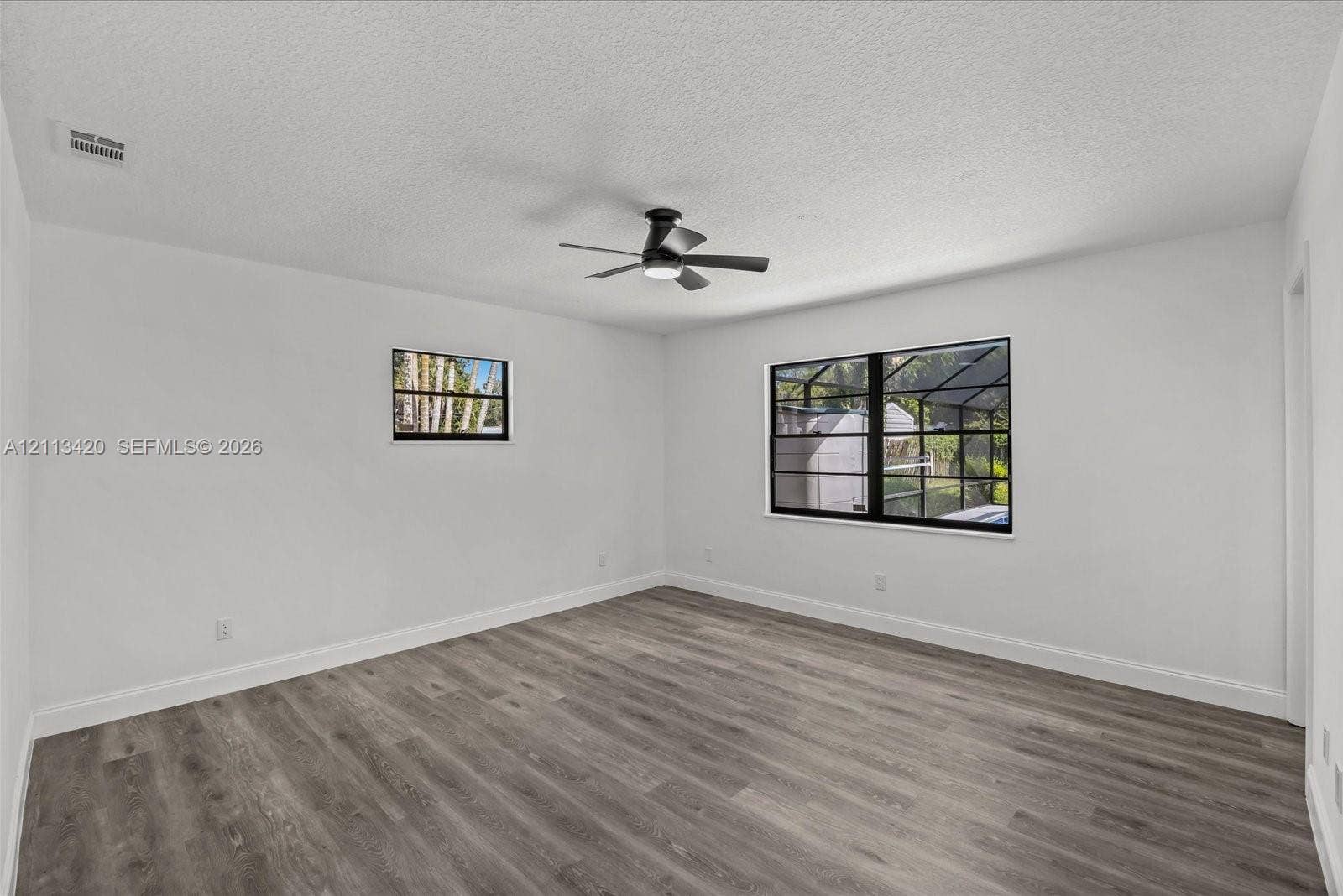 Room featuring wood-finish flooring, matte black window frames, and an integrated ceiling fan with light fixture