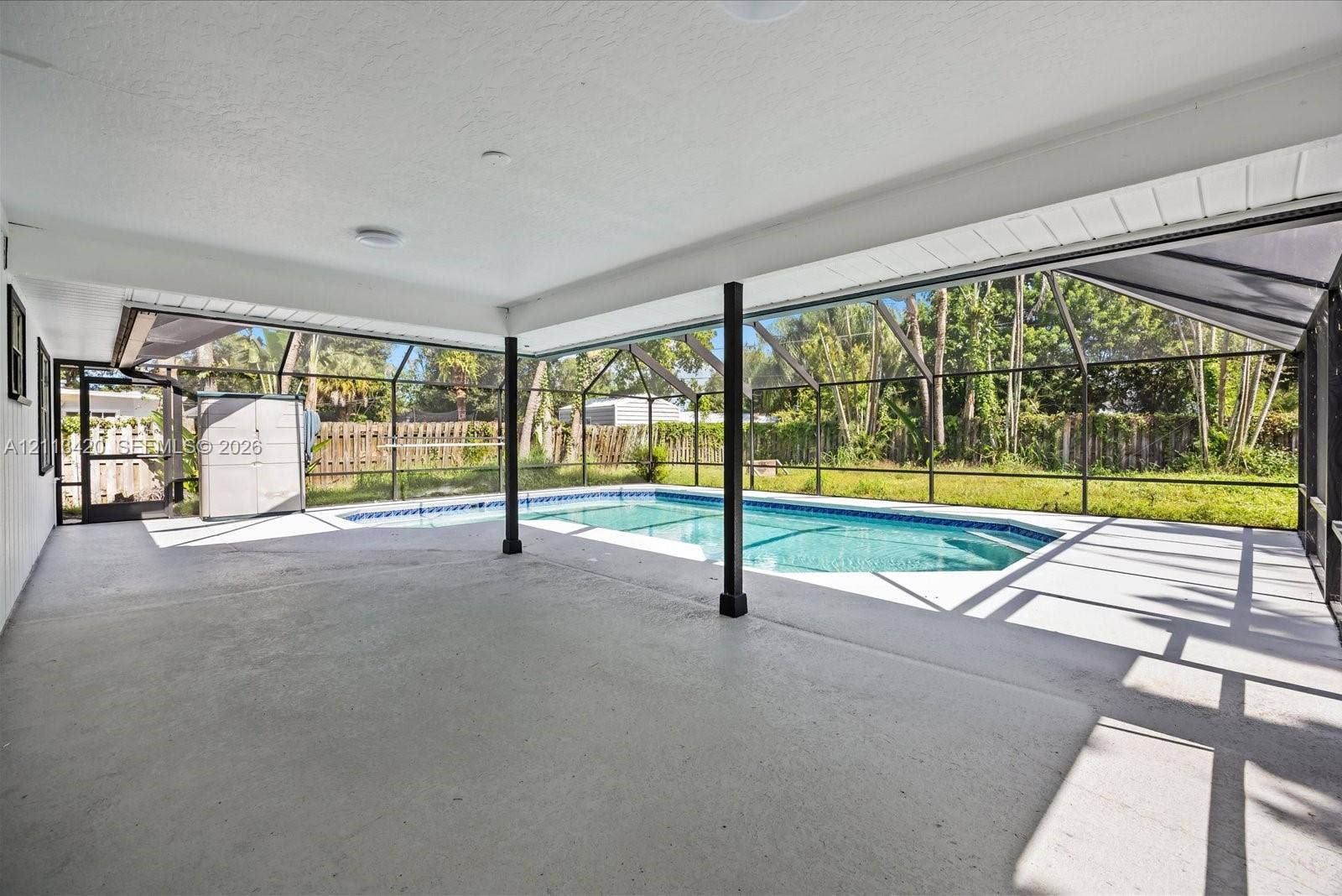 Covered patio featuring concrete flooring and a screened-in enclosure containing a swimming pool