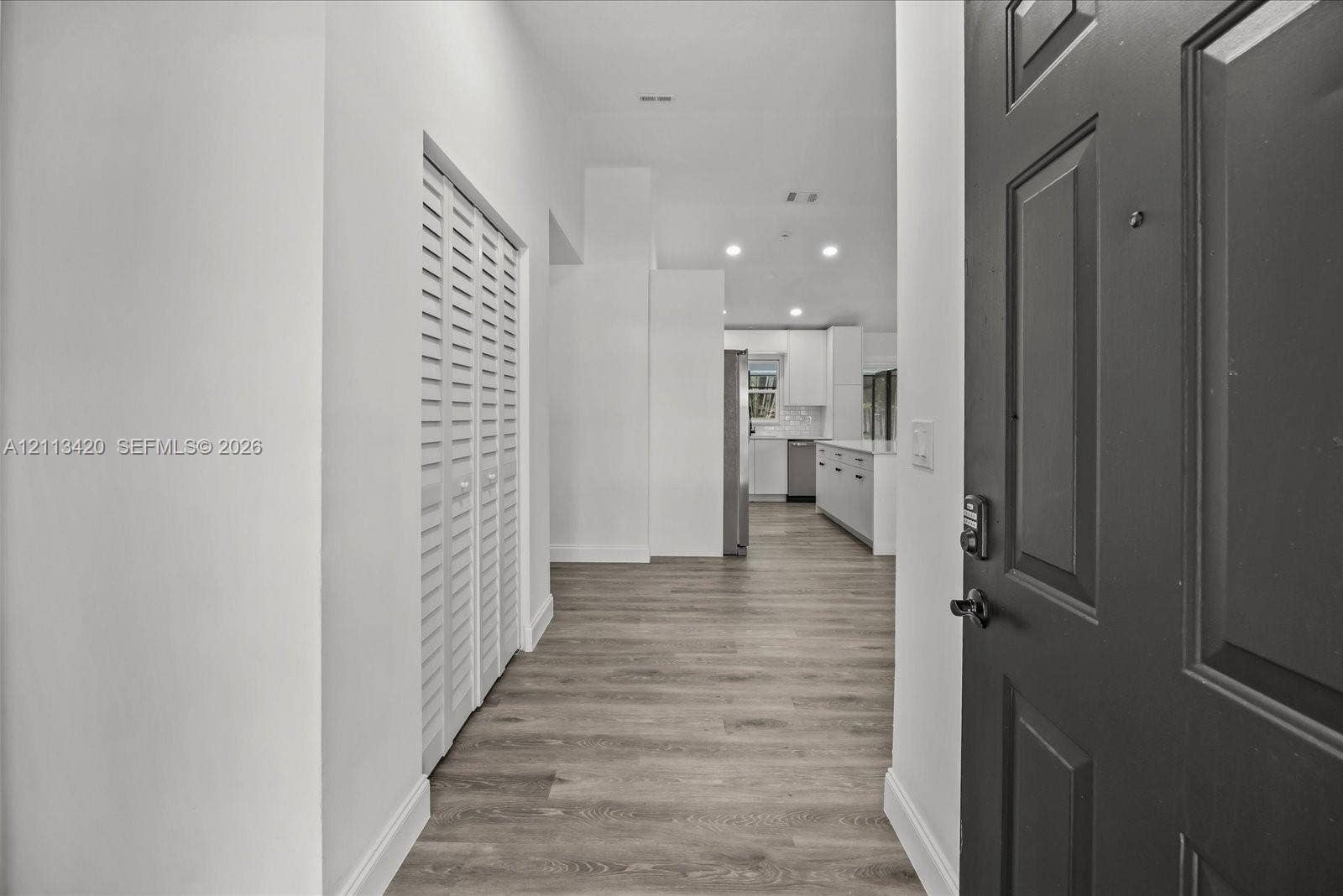 Entryway featuring wood-finish flooring, a paneled door, louvered-style closet doors, and recessed lighting