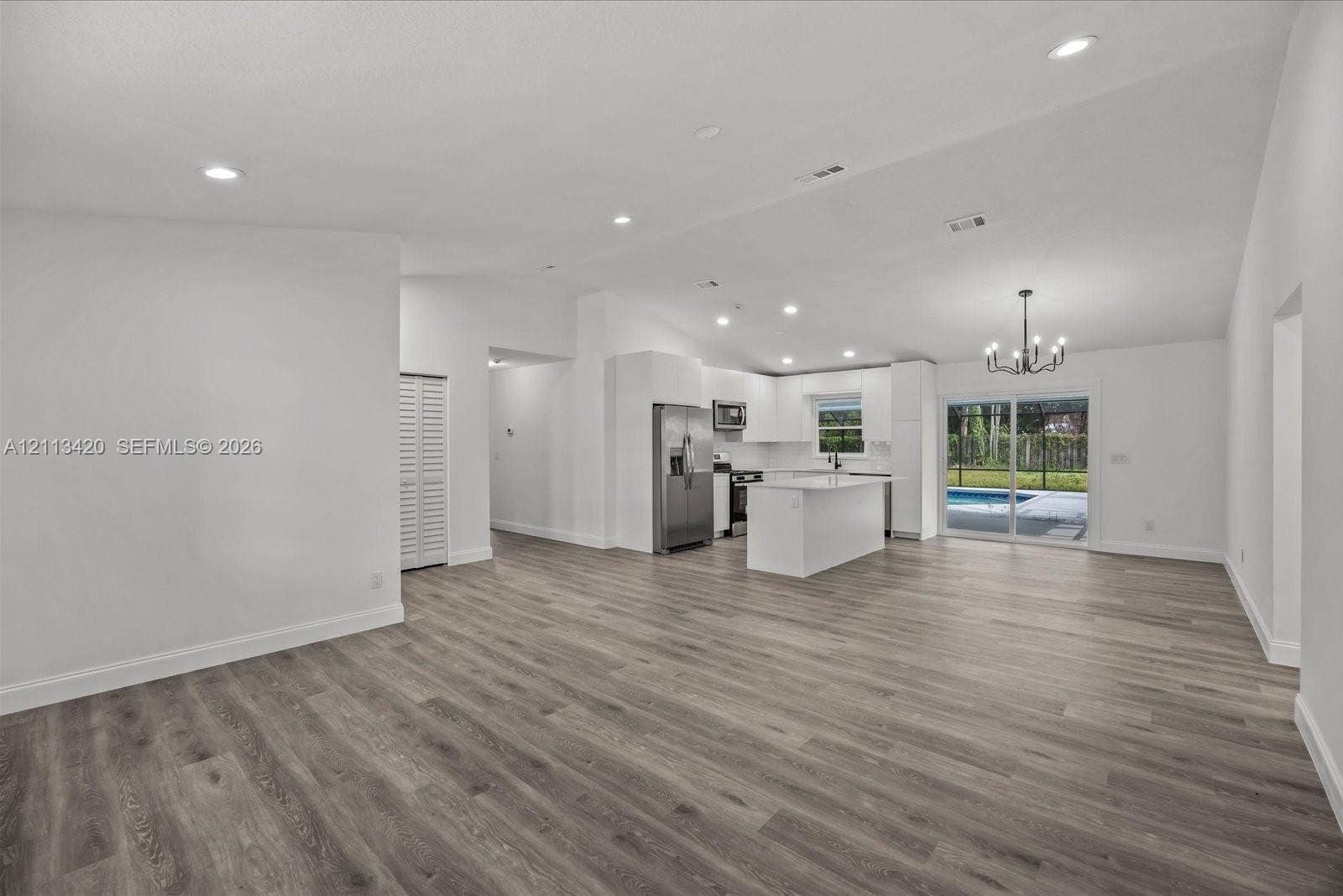 Open floor plan featuring vaulted ceilings, wood-finish flooring, recessed lighting, and a kitchen equipped with a center island and stainless steel appliances