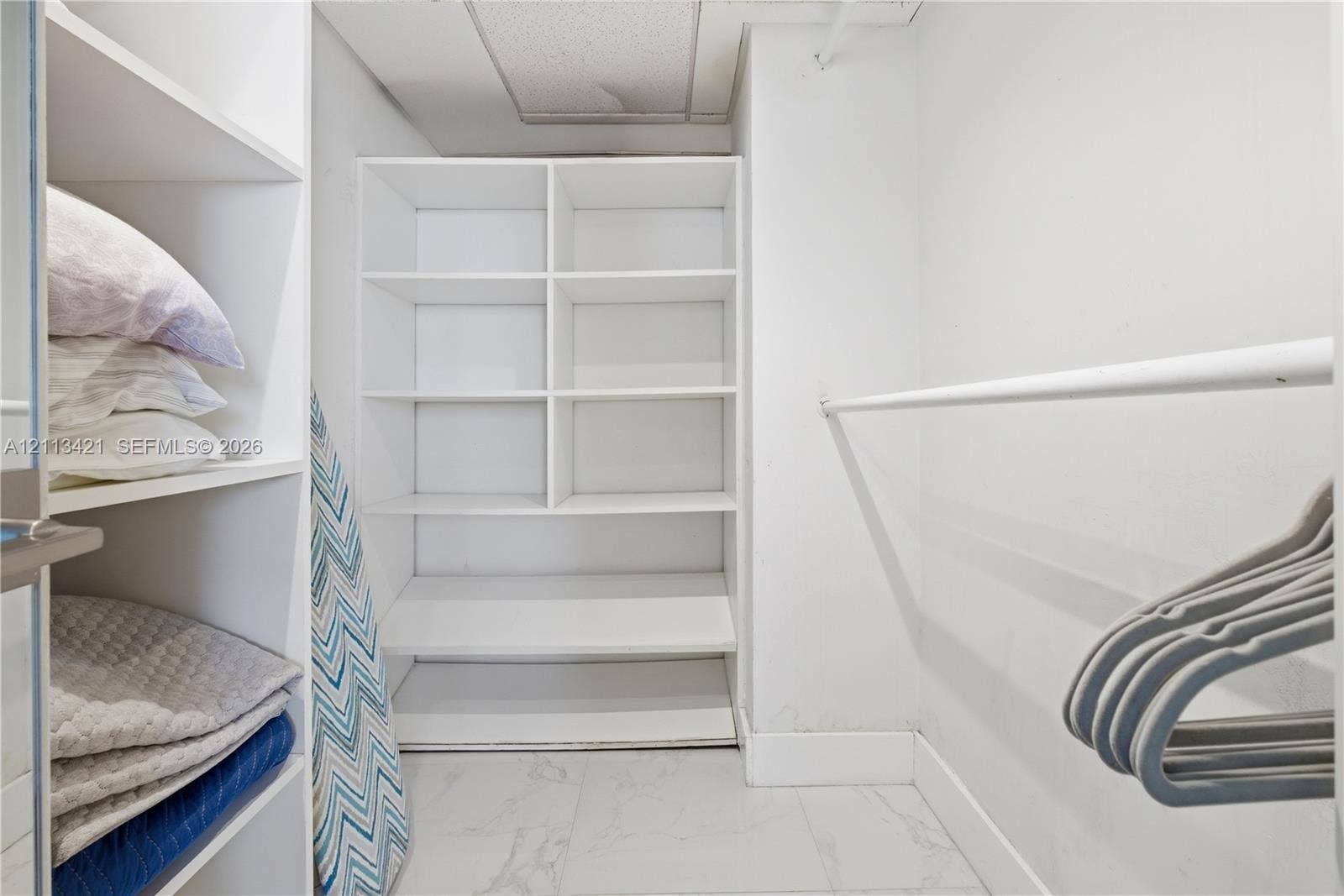 3901 S Ocean Drive, #5L, Hollywood, FL 33019 Walk-in closet featuring white built-in shelving, stone-finish flooring, and a horizontal hanging rod