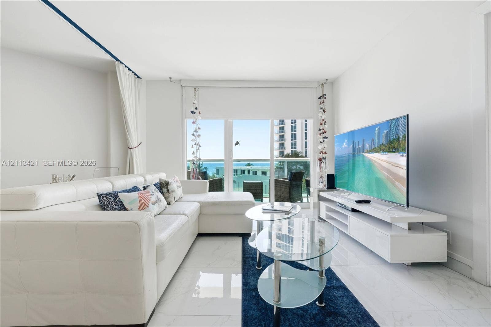 3901 S Ocean Drive, #5L, Hollywood, FL 33019 Living area featuring large-format tile flooring, wall-to-wall glass sliding doors, and a private balcony