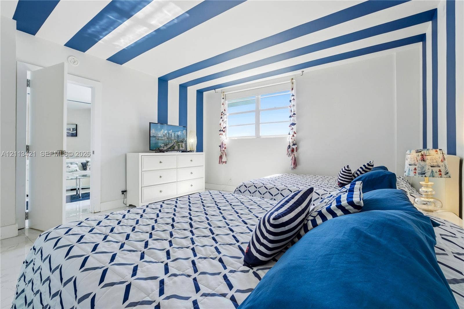 3901 S Ocean Drive, #5L, Hollywood, FL 33019 Room interior featuring smooth-finish light-toned flooring, expansive horizontal sliding windows, and a decorative ceiling treatment with painted structural accents