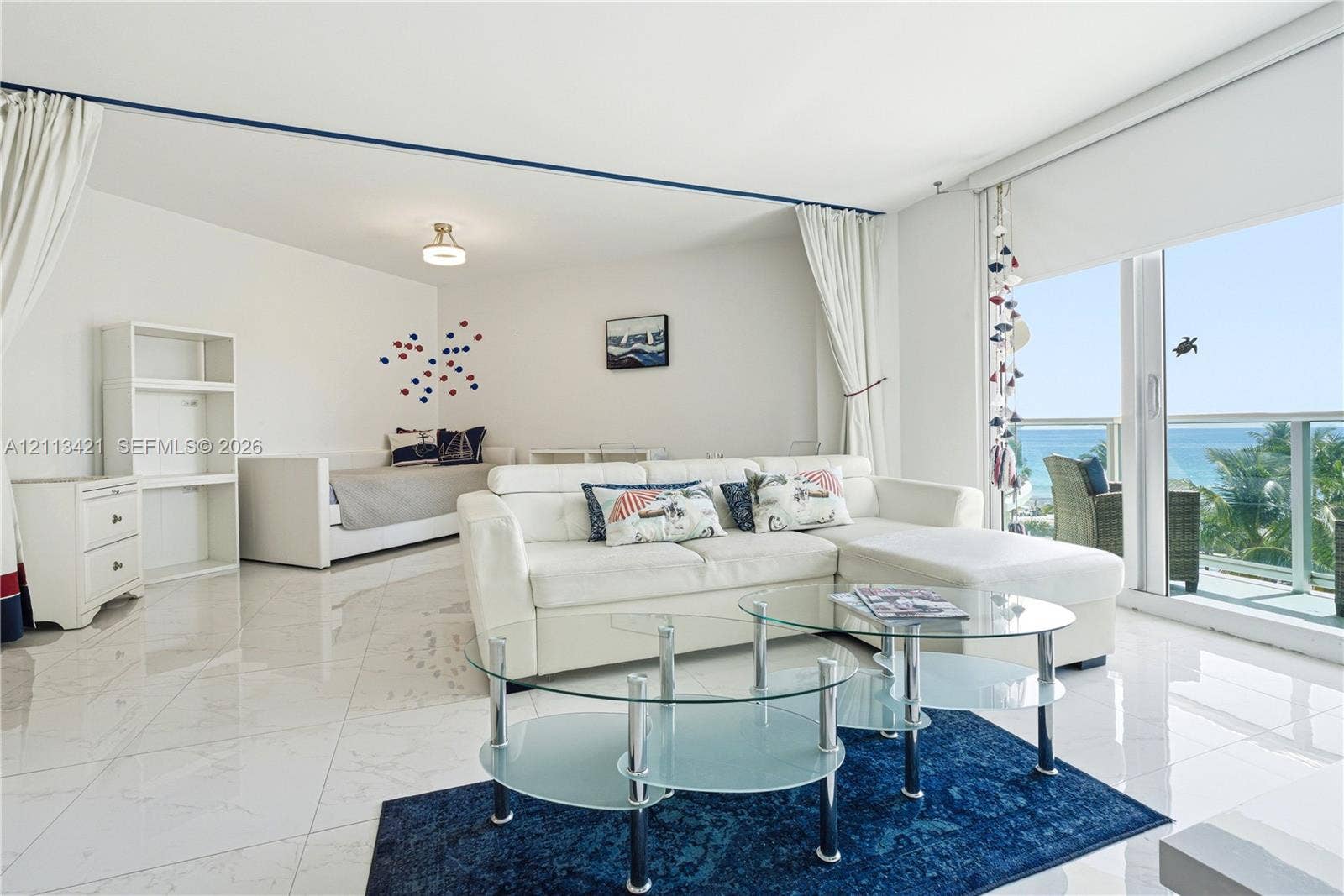 3901 S Ocean Drive, #5L, Hollywood, FL 33019 Polished tile flooring, built-in shelving unit, expansive sliding glass door, and private balcony with ocean backdrop