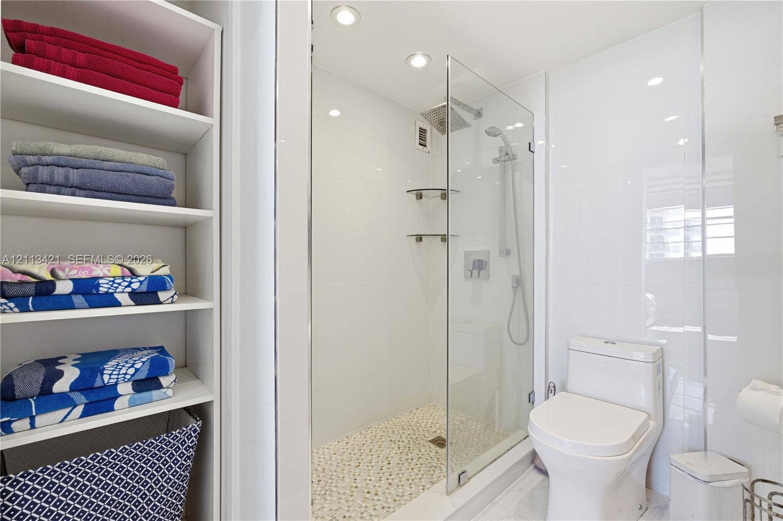 3901 S Ocean Drive, #5L, Hollywood, FL 33019 Walk-in glass enclosed shower with rainfall showerhead, pebble-stone flooring, built-in recessed shelving, and integrated overhead lighting