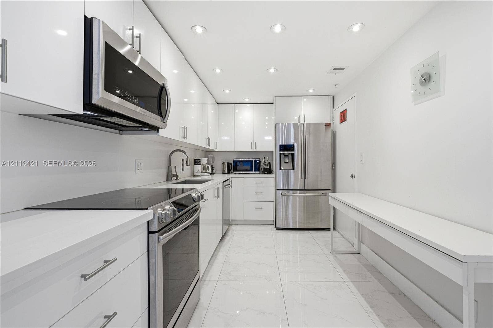 3901 S Ocean Drive, #5L, Hollywood, FL 33019 Contemporary kitchen featuring high-gloss white cabinetry, stainless steel appliances, solid-surface countertops, recessed lighting, and tile flooring
