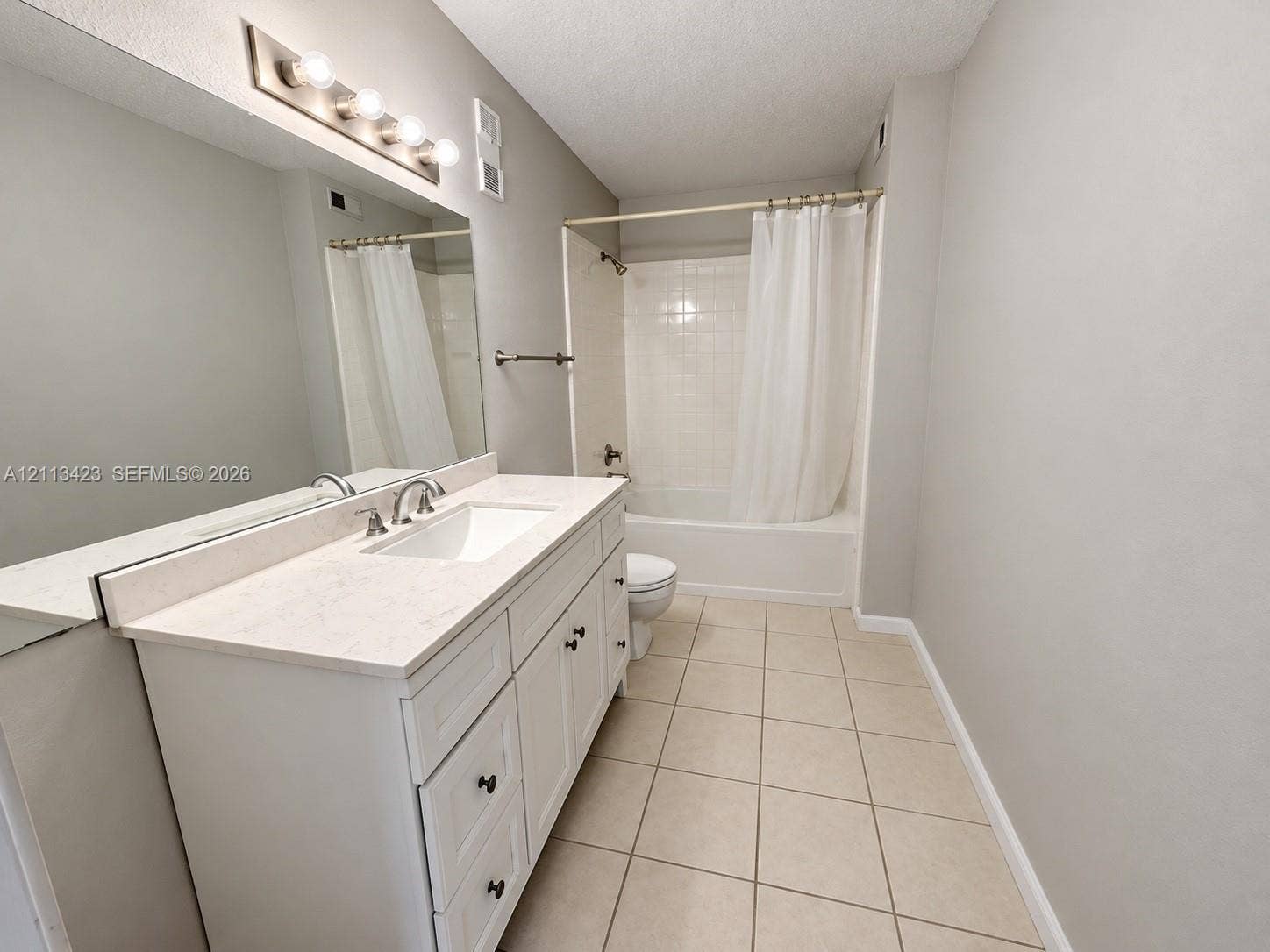 10360 SW 150th Court, #12207, Miami, Miami, FL 33196 Bathroom featuring a white vanity with drawers, a light-toned countertop, a full-width wall mirror, and a tile-surround shower and tub combination with ceramic floor tile