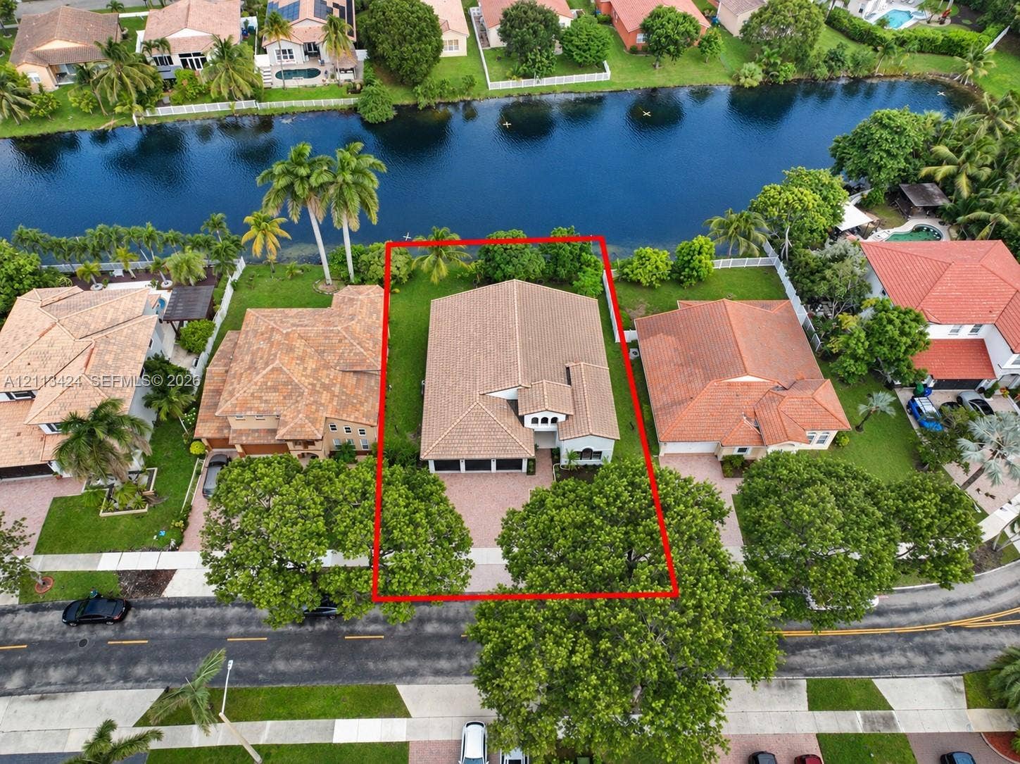 2465 SW 132nd Terrace, Miramar, FL 33027 Waterfront residential property featuring a tiled roof, multi-car garage, brick-paver driveway, and a spacious backyard