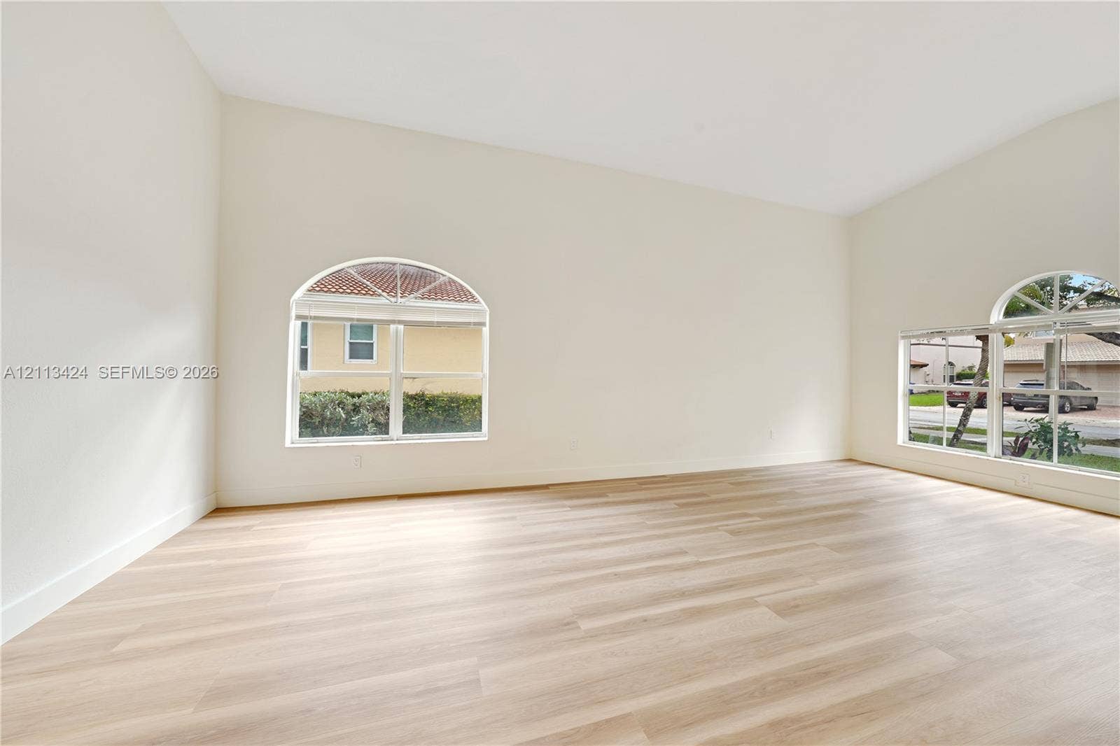 2465 SW 132nd Terrace, Miramar, FL 33027 Spacious interior featuring vaulted ceilings, neutral wall tones, wood-finish flooring, and arched windows