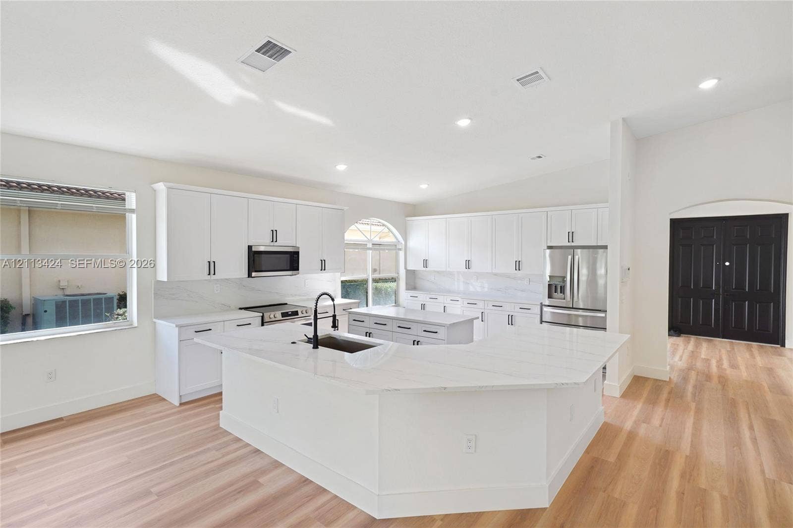 2465 SW 132nd Terrace, Miramar, FL 33027 Kitchen featuring white shaker-style cabinetry, quartz countertops with a waterfall edge island, stainless steel appliances, and wood-finish flooring