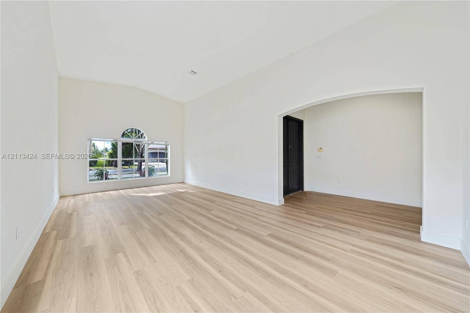 2465 SW 132nd Terrace, Miramar, FL 33027 Vaulted ceilings, wood-finish flooring, and an arched entryway featuring a dark-finish door