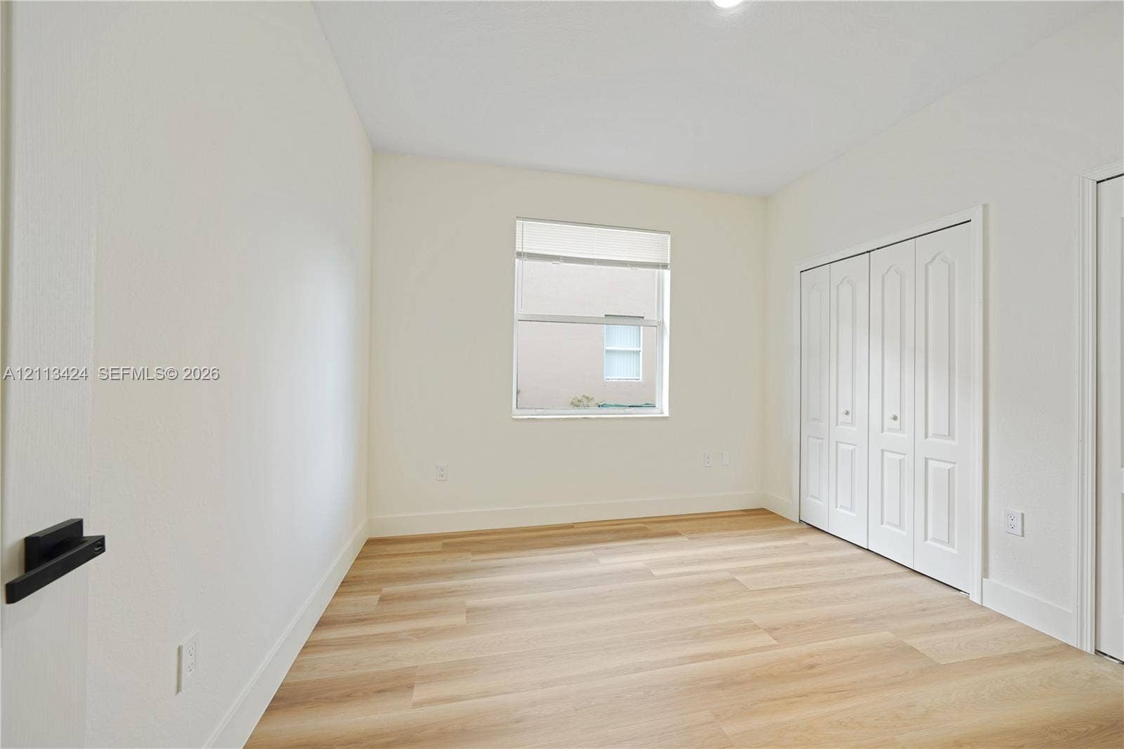 2465 SW 132nd Terrace, Miramar, FL 33027 Room featuring neutral wall paint, wood-finish flooring, a single window, and a built-in closet with four-panel bi-fold doors