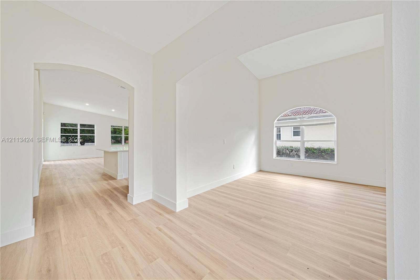2465 SW 132nd Terrace, Miramar, FL 33027 Interior space featuring vaulted ceilings, wood-finish flooring, an arched window, and architectural arched openings