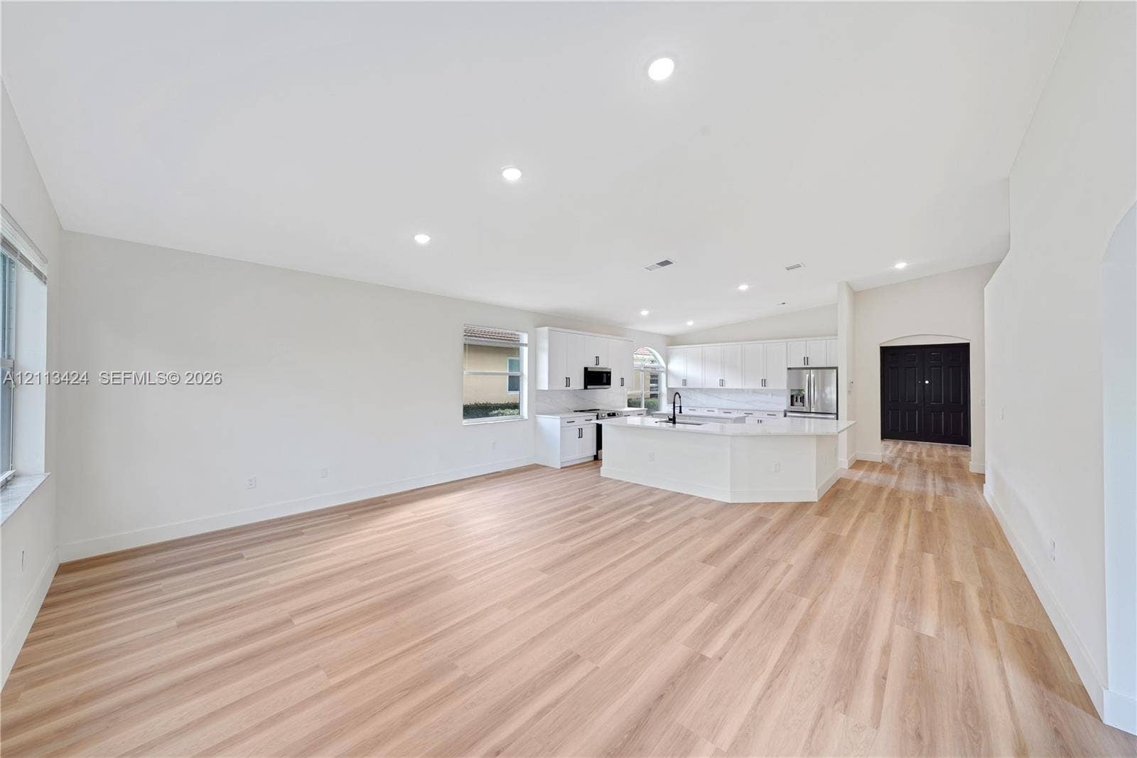 2465 SW 132nd Terrace, Miramar, FL 33027 Open concept kitchen and living area featuring wood-finish flooring, white cabinetry, quartz countertops, a central island, and recessed lighting