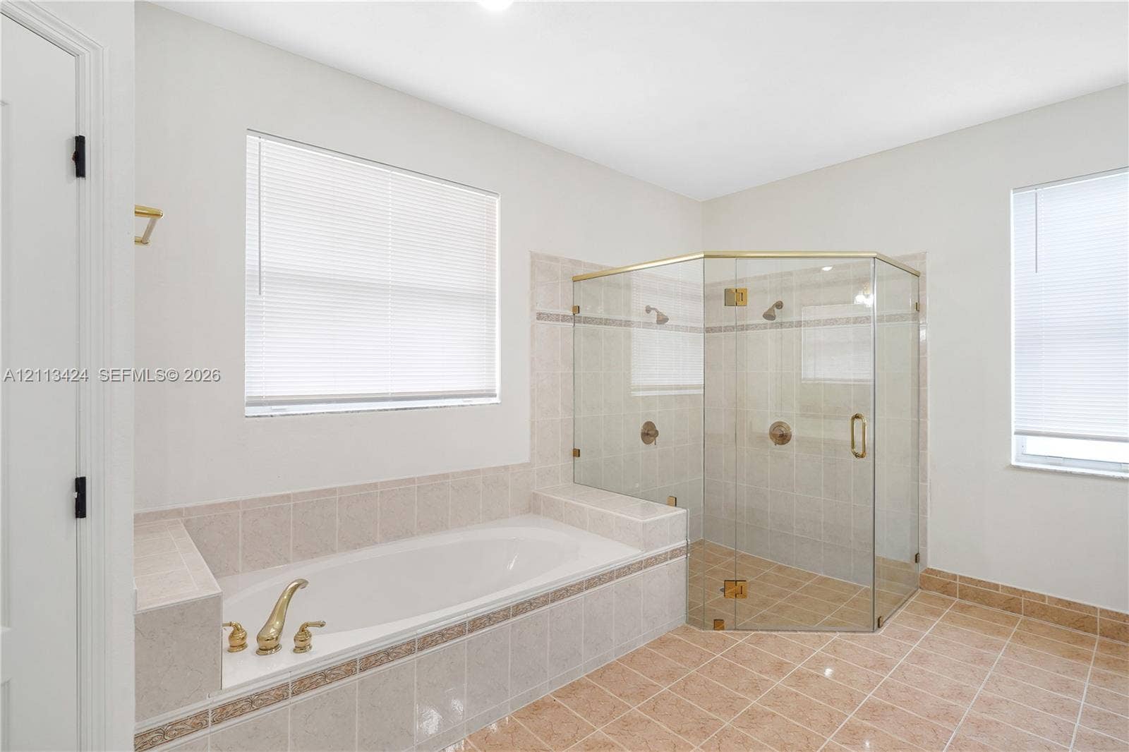2465 SW 132nd Terrace, Miramar, FL 33027 Soaking tub with tiled surround, glass-enclosed shower with gold-tone hardware, and ceramic tile flooring