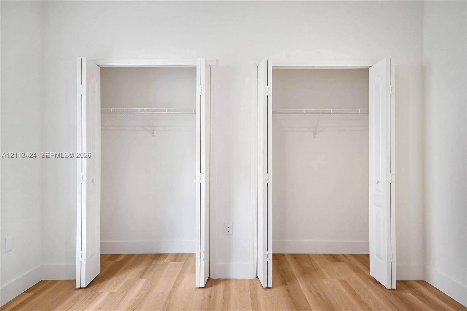 2465 SW 132nd Terrace, Miramar, FL 33027 Dual closets featuring white bi-fold doors and integrated wire shelving, complemented by wood-finish flooring