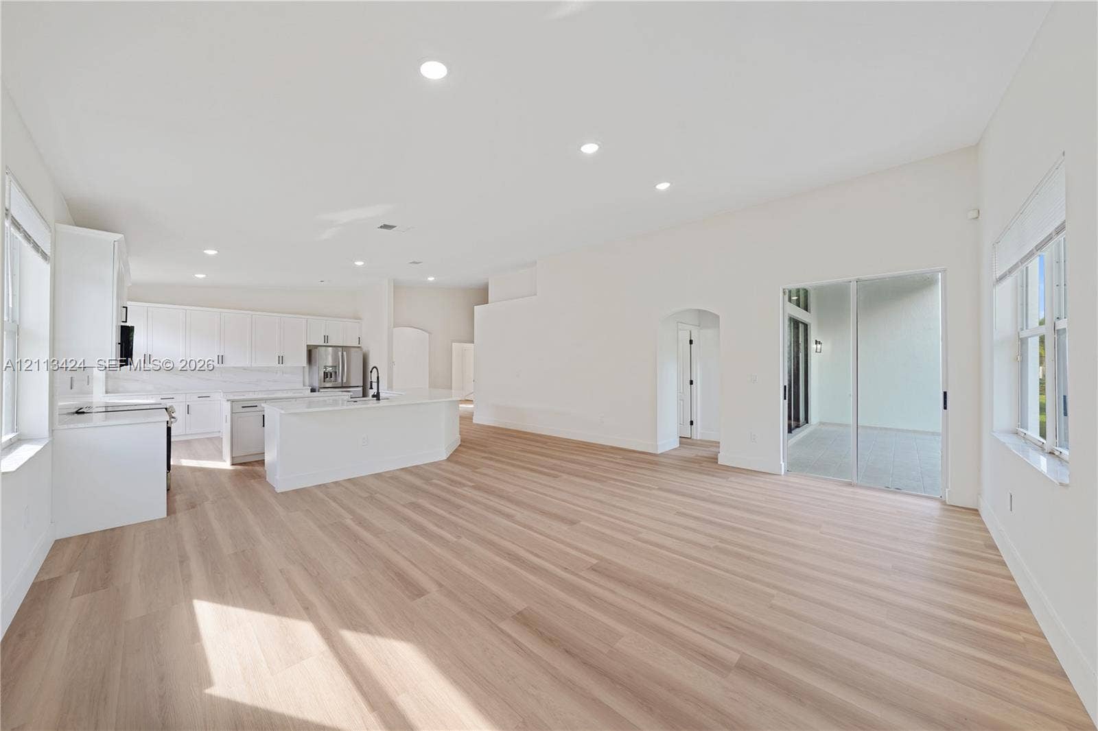 2465 SW 132nd Terrace, Miramar, FL 33027 Open-concept kitchen featuring white cabinetry, a center island with quartz countertops, wood-finish flooring, recessed lighting, and sliding glass doors