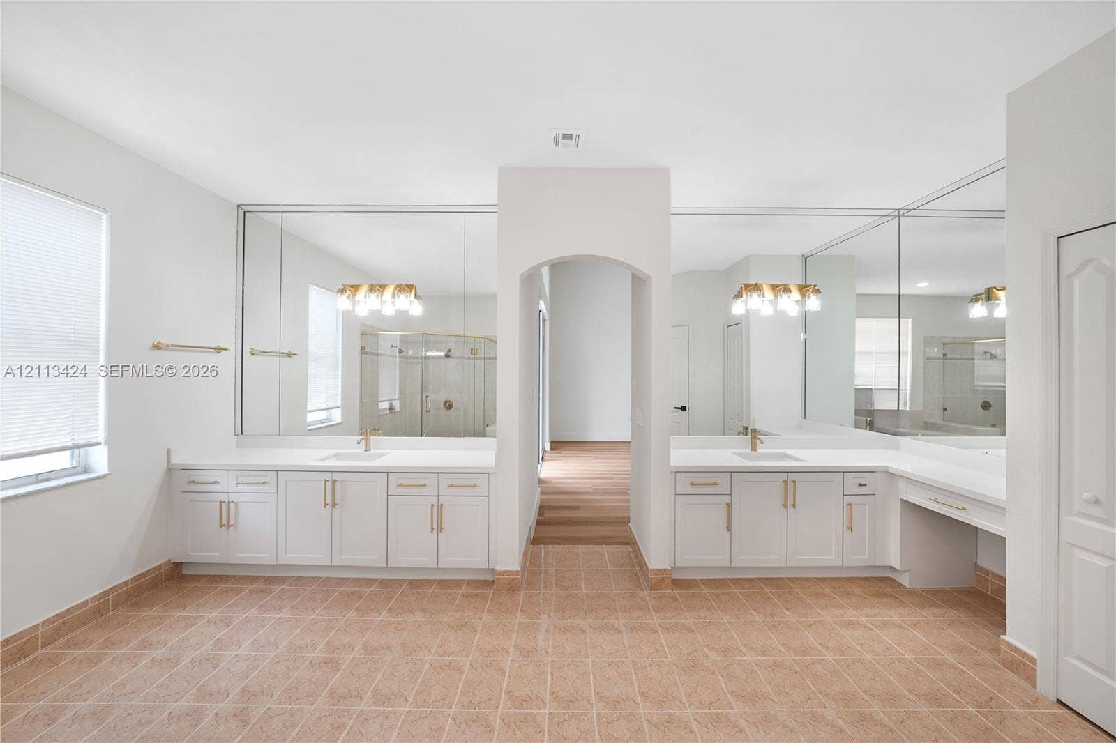 2465 SW 132nd Terrace, Miramar, FL 33027 Dual-vanity cabinetry with white countertops, integrated sinks, brass-finish hardware, full-width vanity mirrors, and ceramic tile flooring