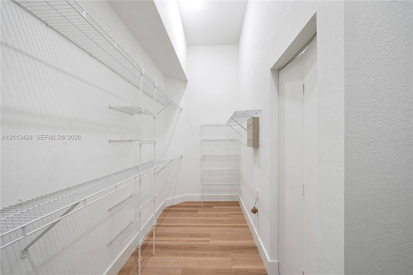 2465 SW 132nd Terrace, Miramar, FL 33027 Walk-in closet featuring wood-finish flooring, white walls, vaulted ceiling, and tiered white wire shelving