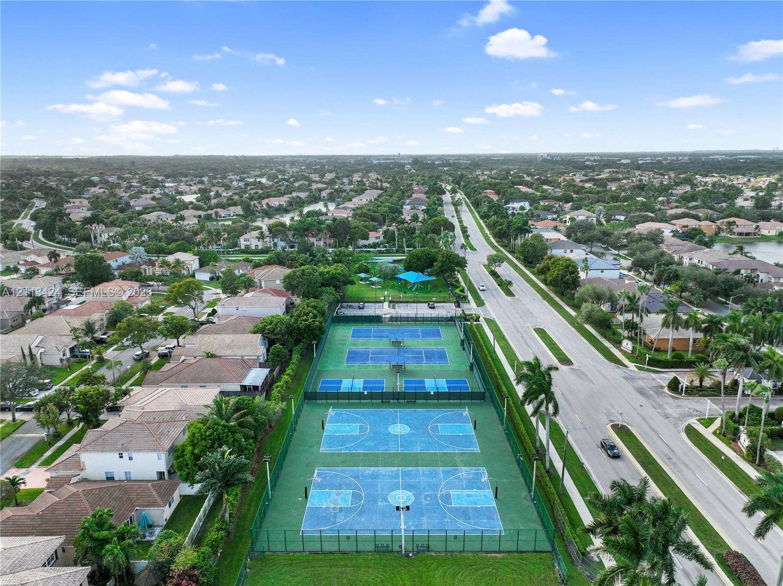 2465 SW 132nd Terrace, Miramar, FL 33027 Aerial perspective of recreational facilities including two fenced tennis courts and two basketball courts with integrated lighting