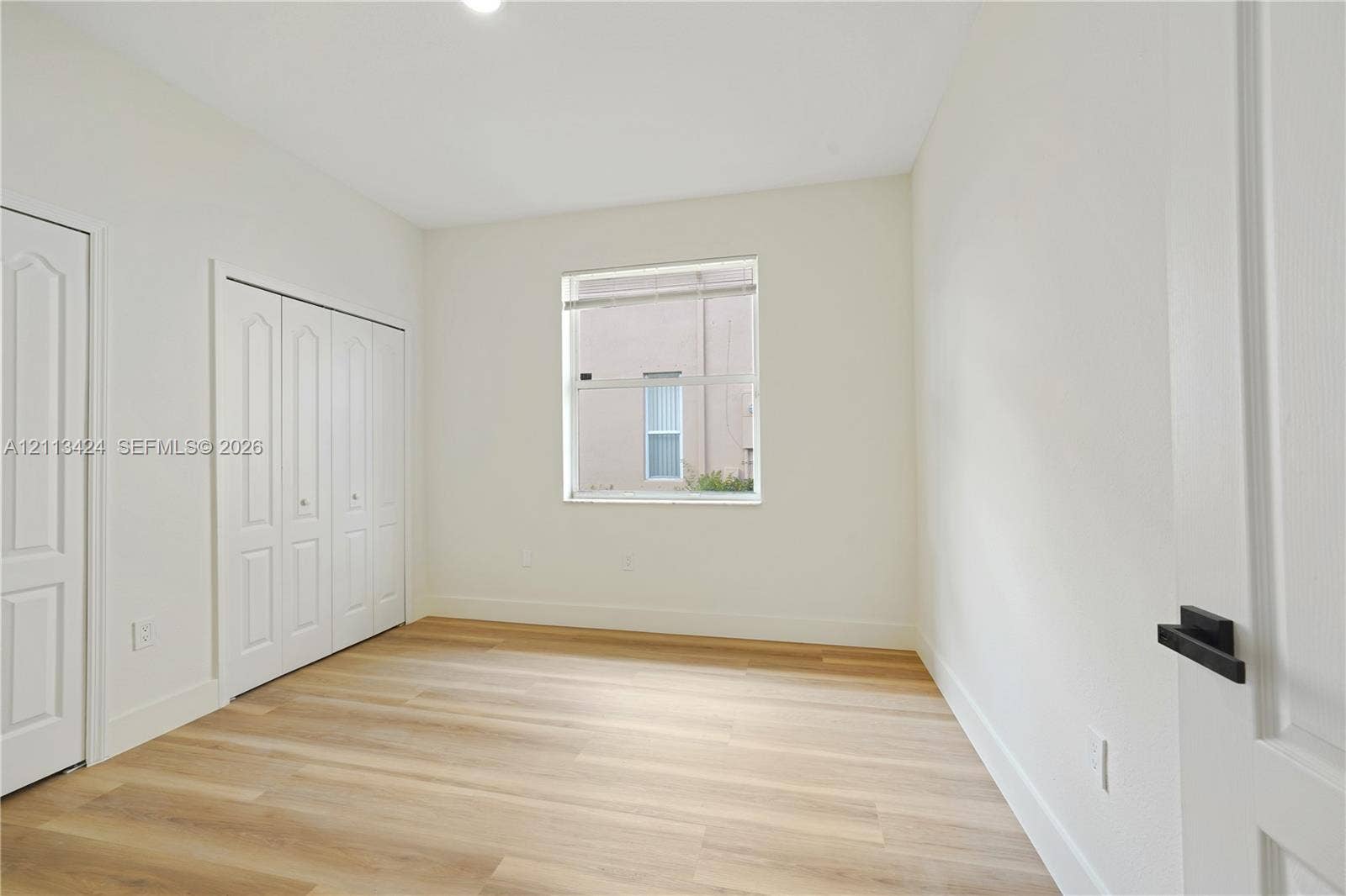 2465 SW 132nd Terrace, Miramar, FL 33027 Neutral-toned interior featuring wood-finish flooring, a single-hung window, and a multi-panel closet door with matte black hardware