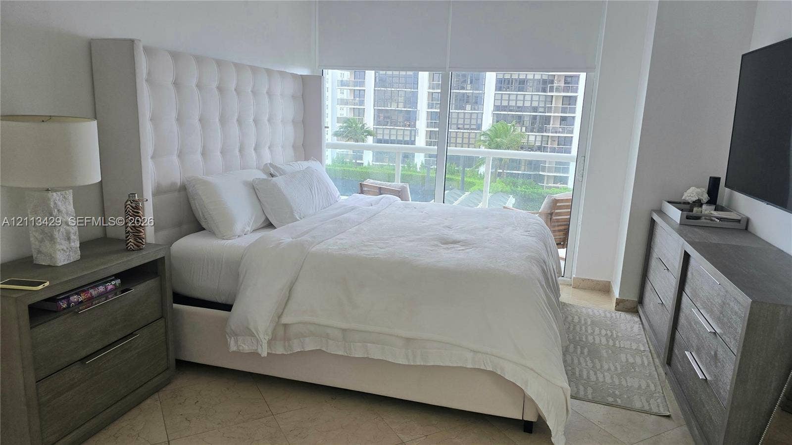 6365 Collins Avenue, #909, Miami Beach, FL 33141 Floor-to-ceiling windows featuring automated roller shades, neutral stone flooring, and expansive natural light