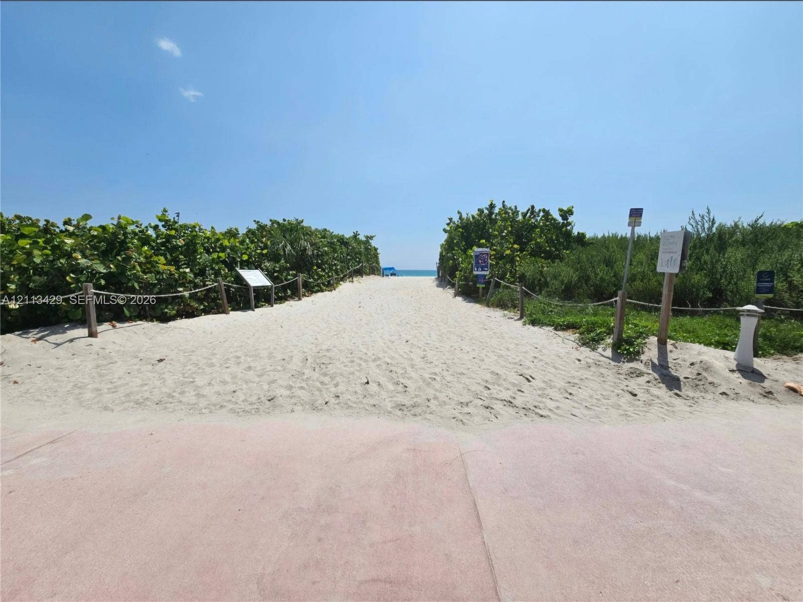 6365 Collins Avenue, #909, Miami Beach, FL 33141 Sandy path access featuring a paved approach, natural vegetation border, and rope fencing