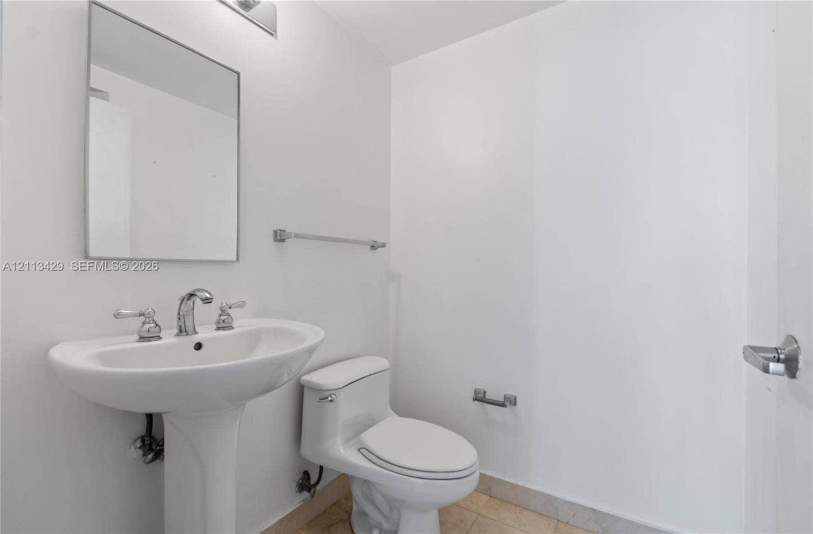 6365 Collins Avenue, #909, Miami Beach, FL 33141 Pedestal sink with polished chrome widespread faucet, frameless wall mirror, chrome light fixture, and tile flooring