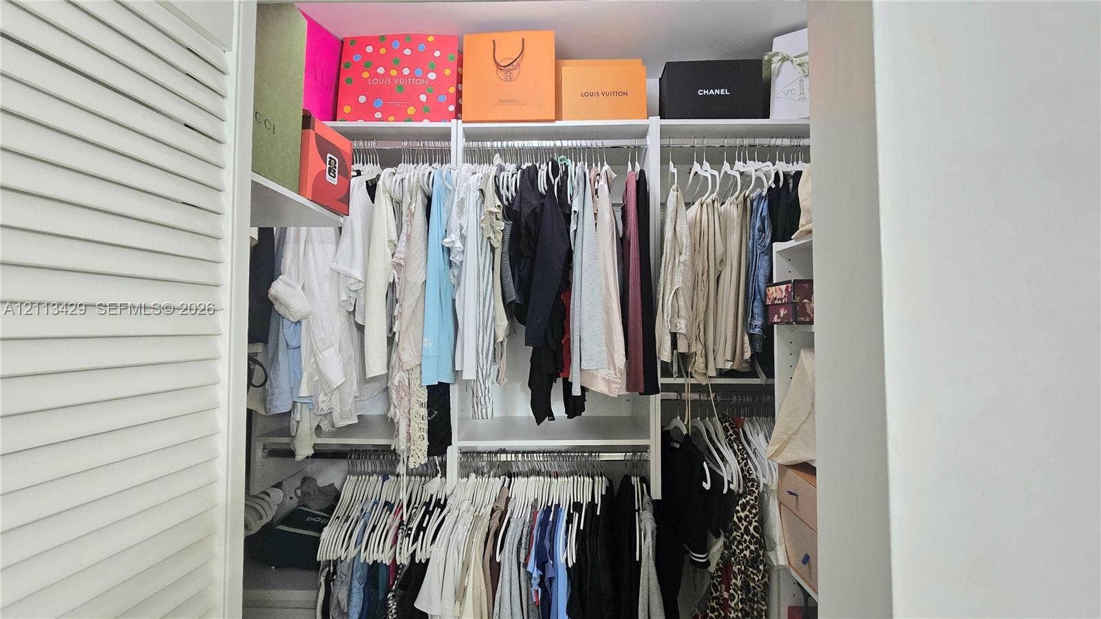 6365 Collins Avenue, #909, Miami Beach, FL 33141 Custom closet organization system featuring white laminate shelving, adjustable vertical supports, and dual-level hanging rods