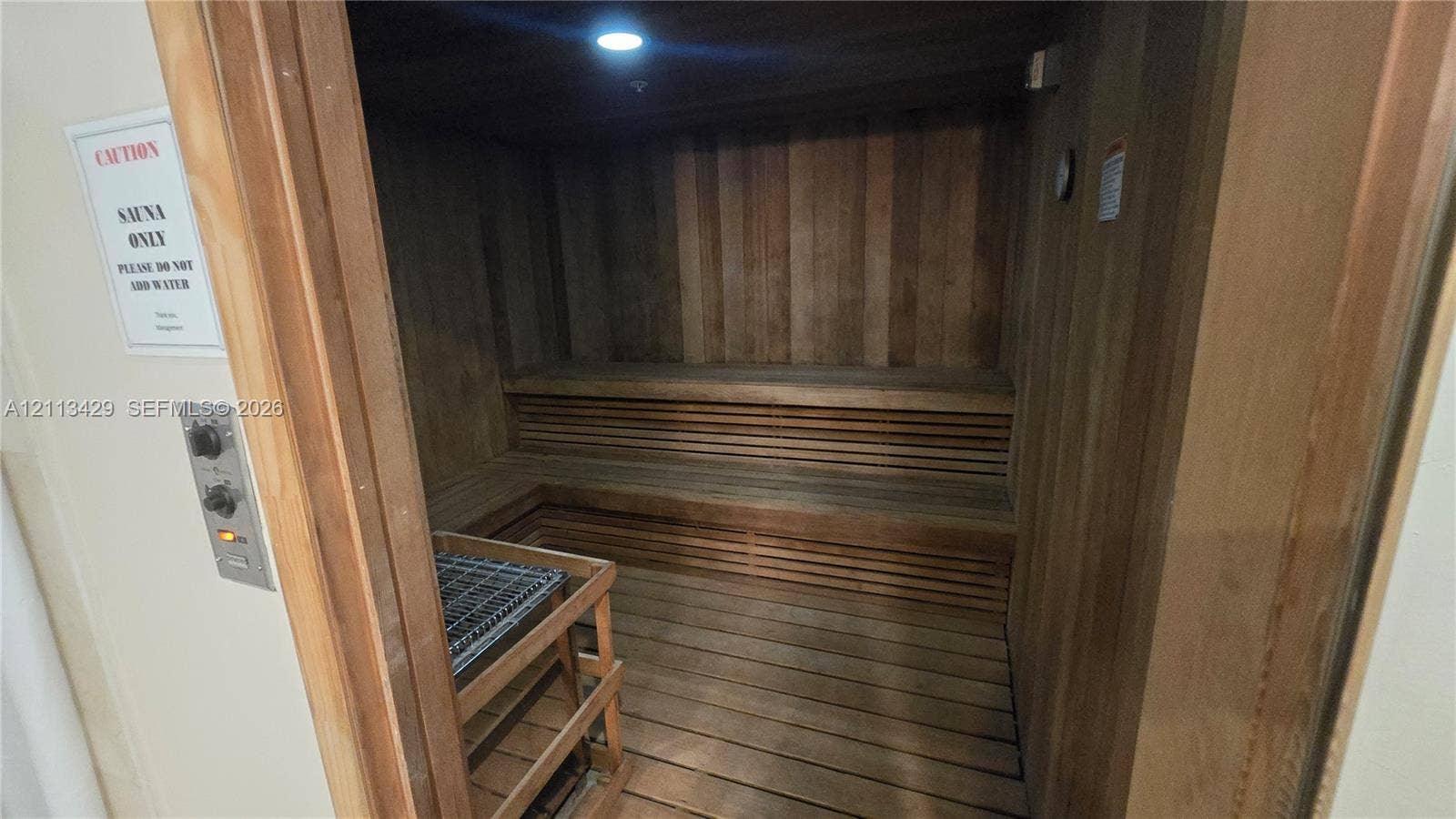 6365 Collins Avenue, #909, Miami Beach, FL 33141 Sauna featuring wood-paneled walls, tiered bench seating, slated floorboards, and a recessed heating element