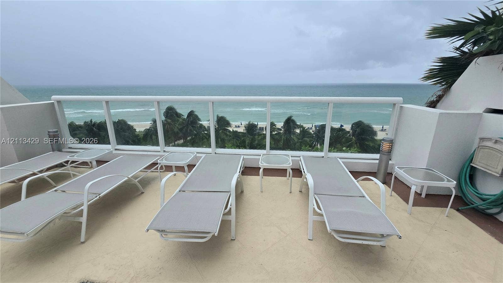 6365 Collins Avenue, #909, Miami Beach, FL 33141 Private balcony with stone flooring, custom glass and white metal railing, and ocean backdrop