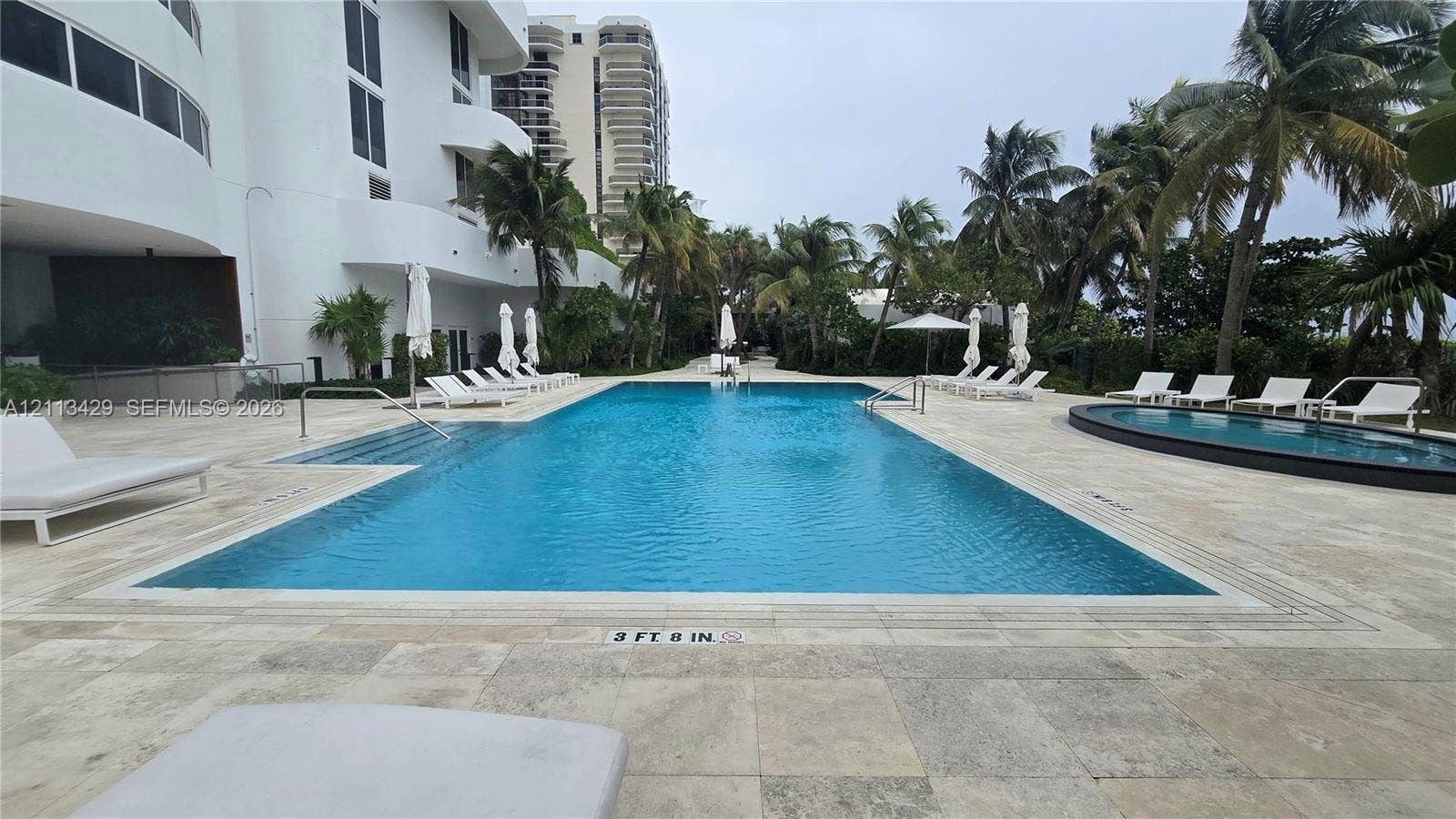 6365 Collins Avenue, #909, Miami Beach, FL 33141 Swimming pool with stone-tiled deck, integrated lap lanes, secondary circular pool, and tropical palm tree landscaping