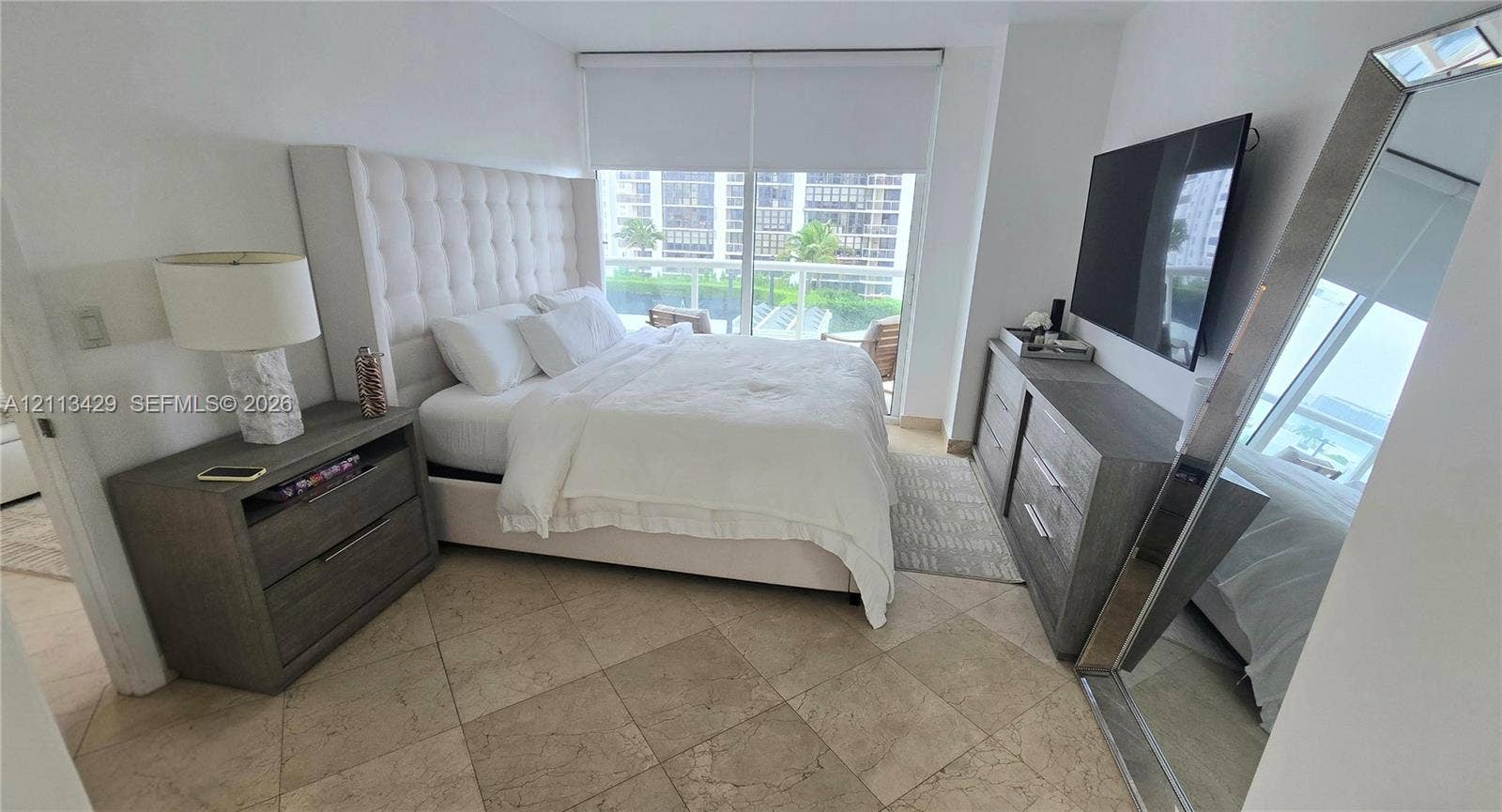 6365 Collins Avenue, #909, Miami Beach, FL 33141 Spacious room featuring neutral stone tile flooring, floor-to-ceiling glass sliding doors, and a private balcony